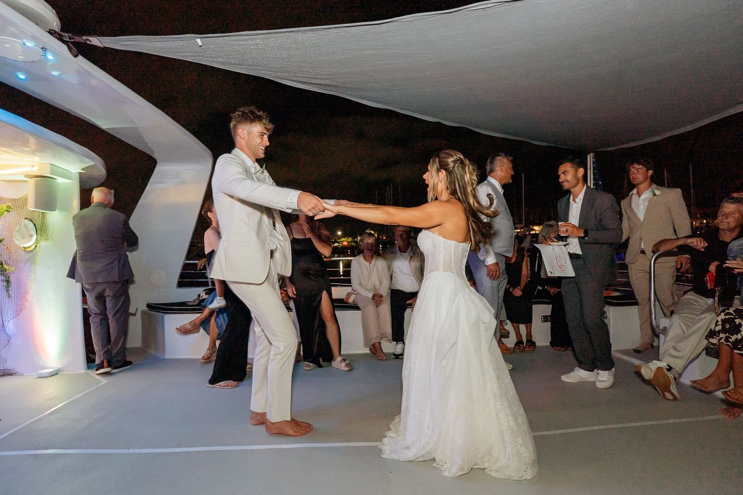 Newlyweds share romantic first dance under tent at elegant evening wedding reception with guests.