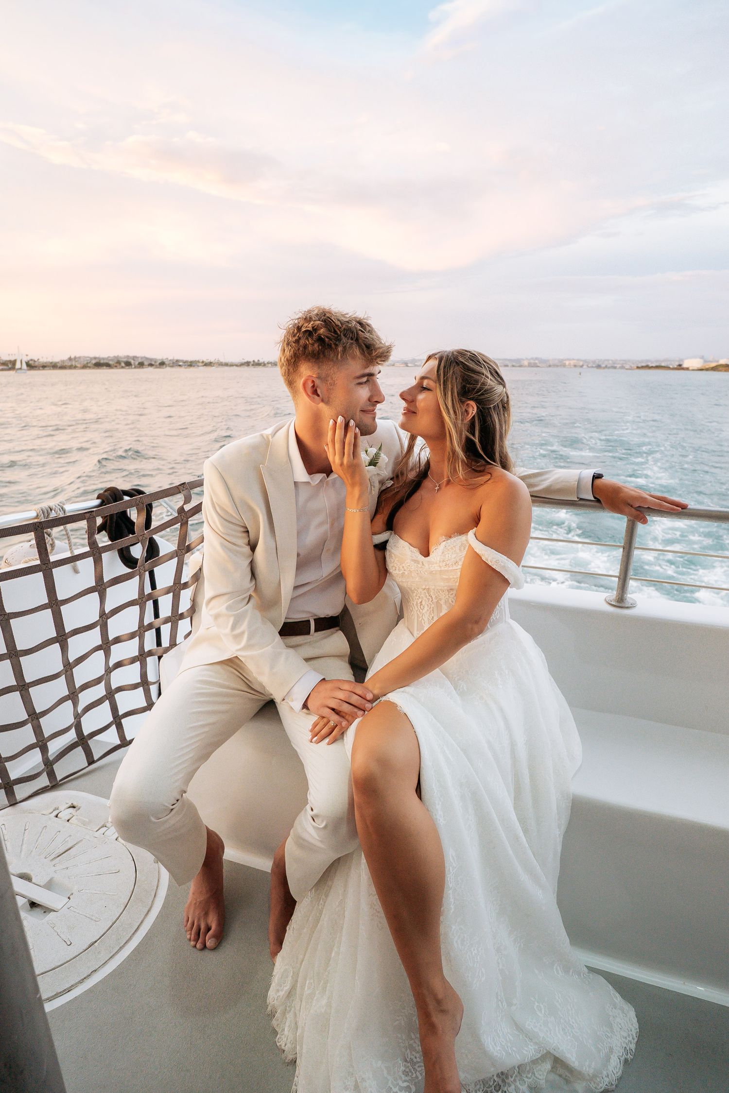 Newlywed couple in wedding attire sharing a romantic moment on a luxury yacht at sunset.