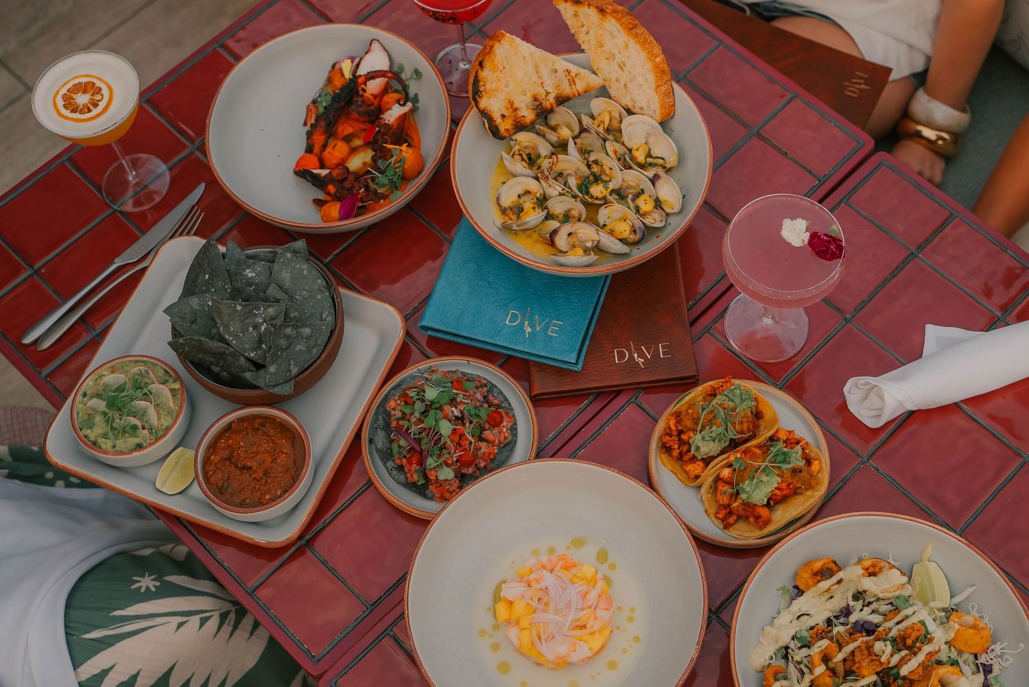 Overhead view of a vibrant spread of gourmet dishes and appetizers on a red checkered tablecloth at a restaurant.