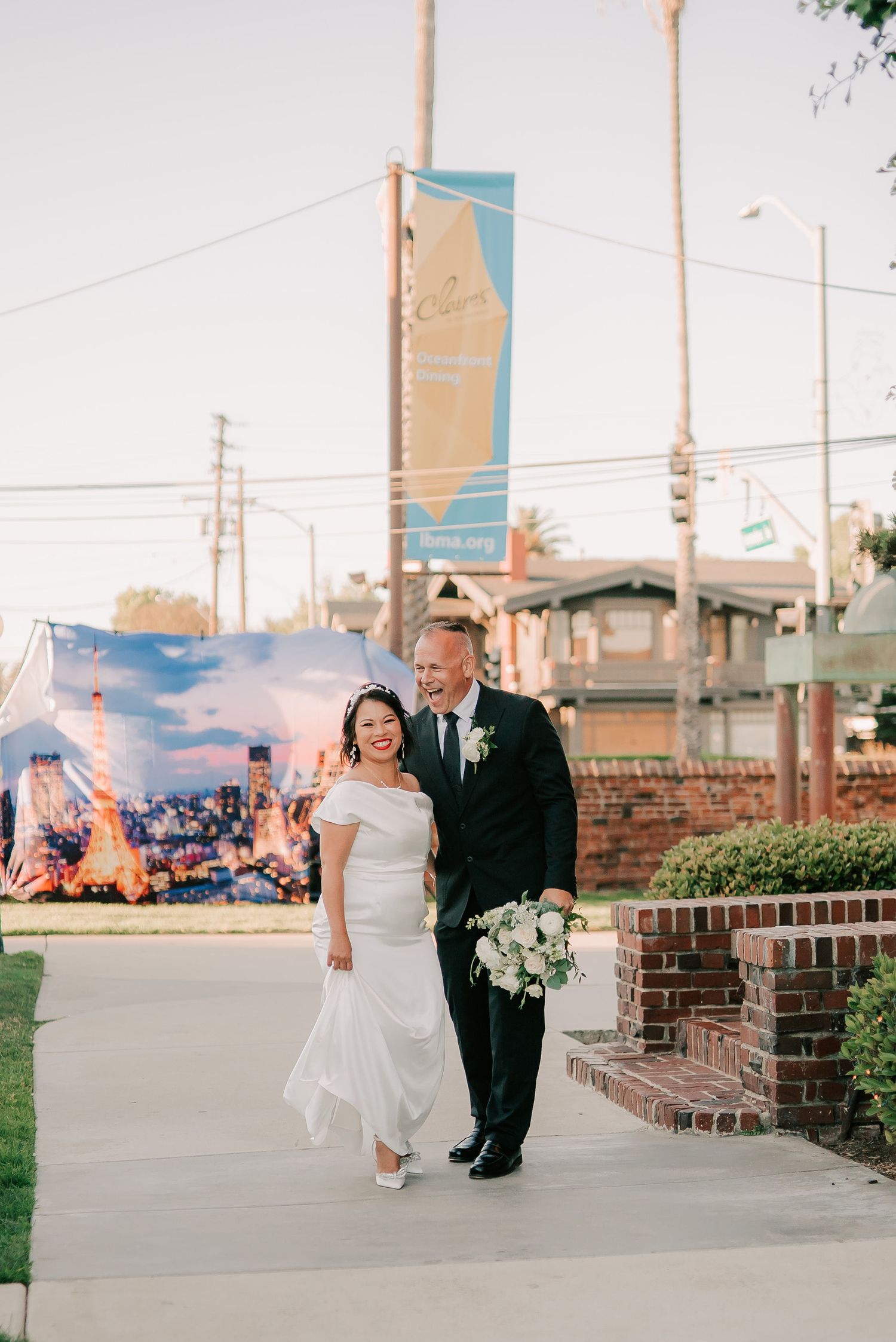 Bride and groom walking together outdoors after wedding ceremony, smiling joyfully, bride holding white bouquet.