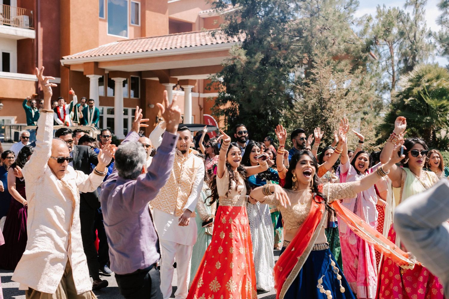 Joyful Indian wedding baraat celebration with bride in red lehenga and guests dancing.