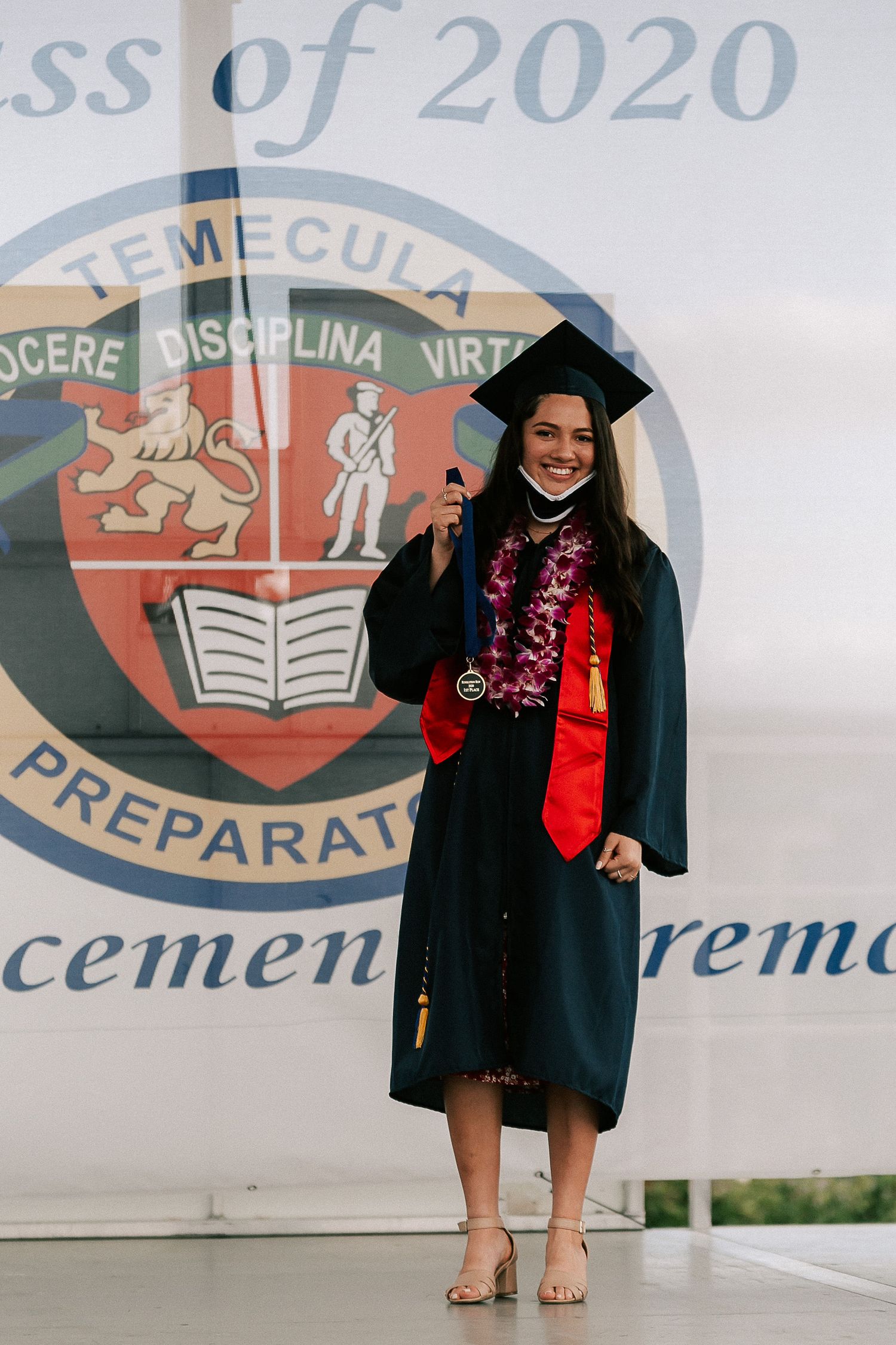 Smiling female graduate in black cap and gown holding diploma at Temecula Preparatory School Class of 2020 ceremony.