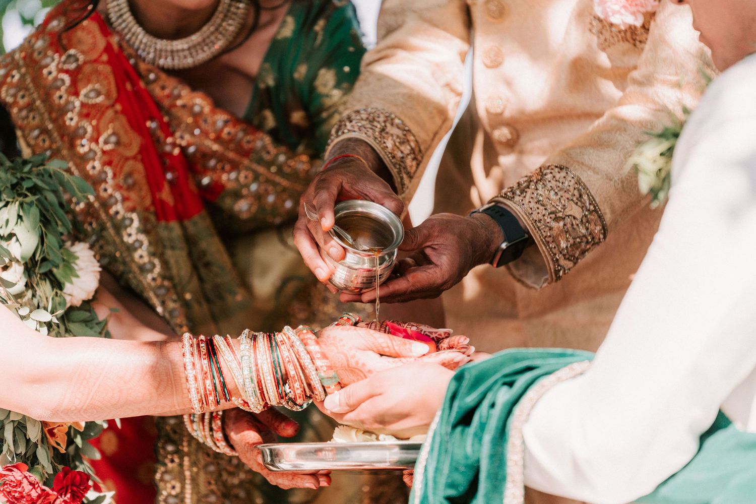 Close-up of traditional Indian wedding ritual with ornate bangles and ceremonial vessel.