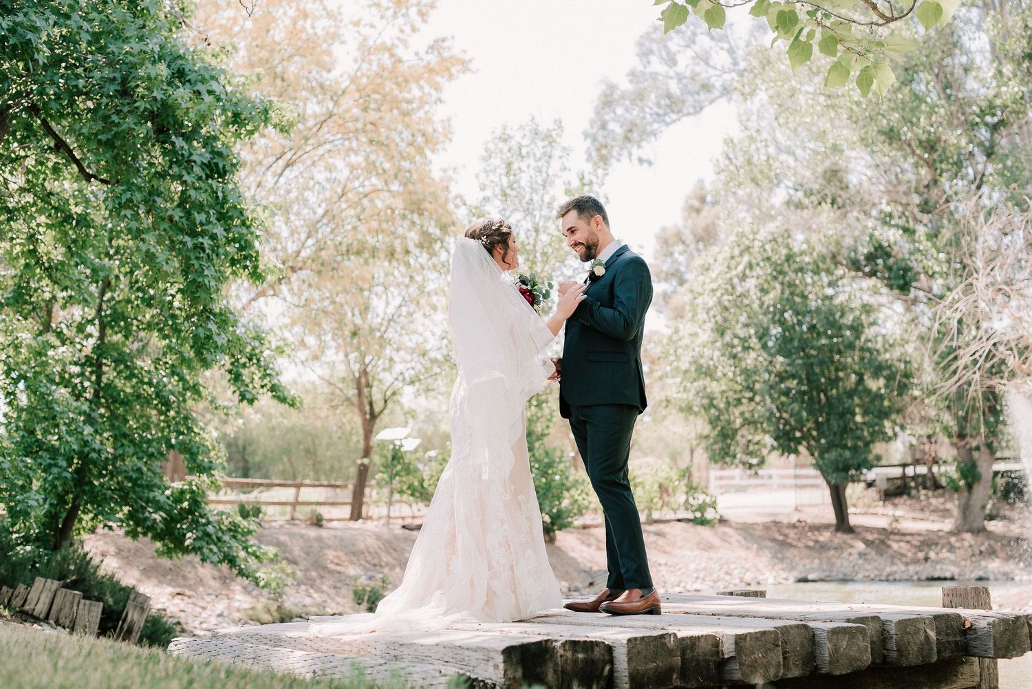 Bride and groom share vows outdoors surrounded by lush green trees on their wedding day.