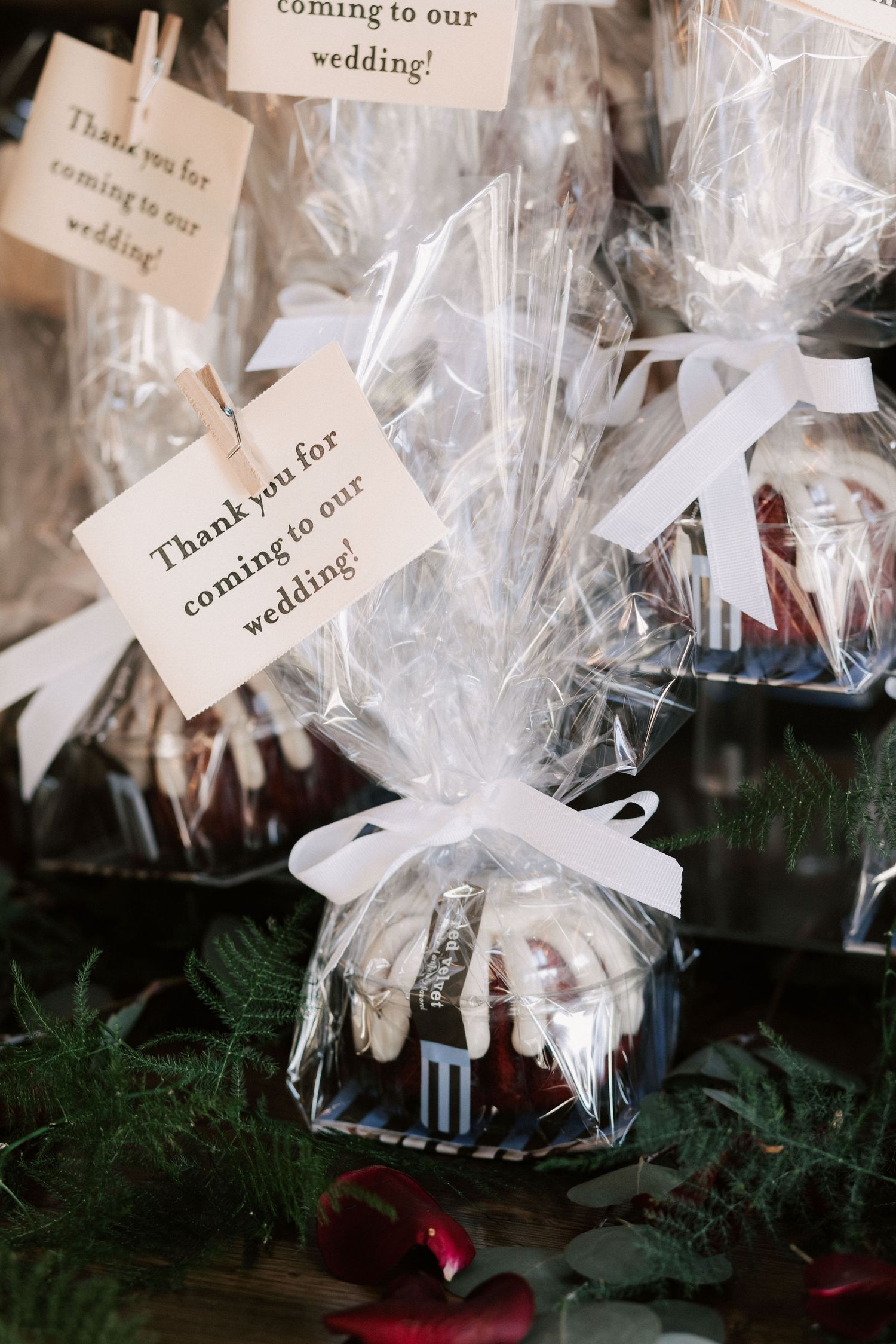 Elegant mini bundt cake wedding favors wrapped in clear cellophane with white ribbon and thank you tags on display.