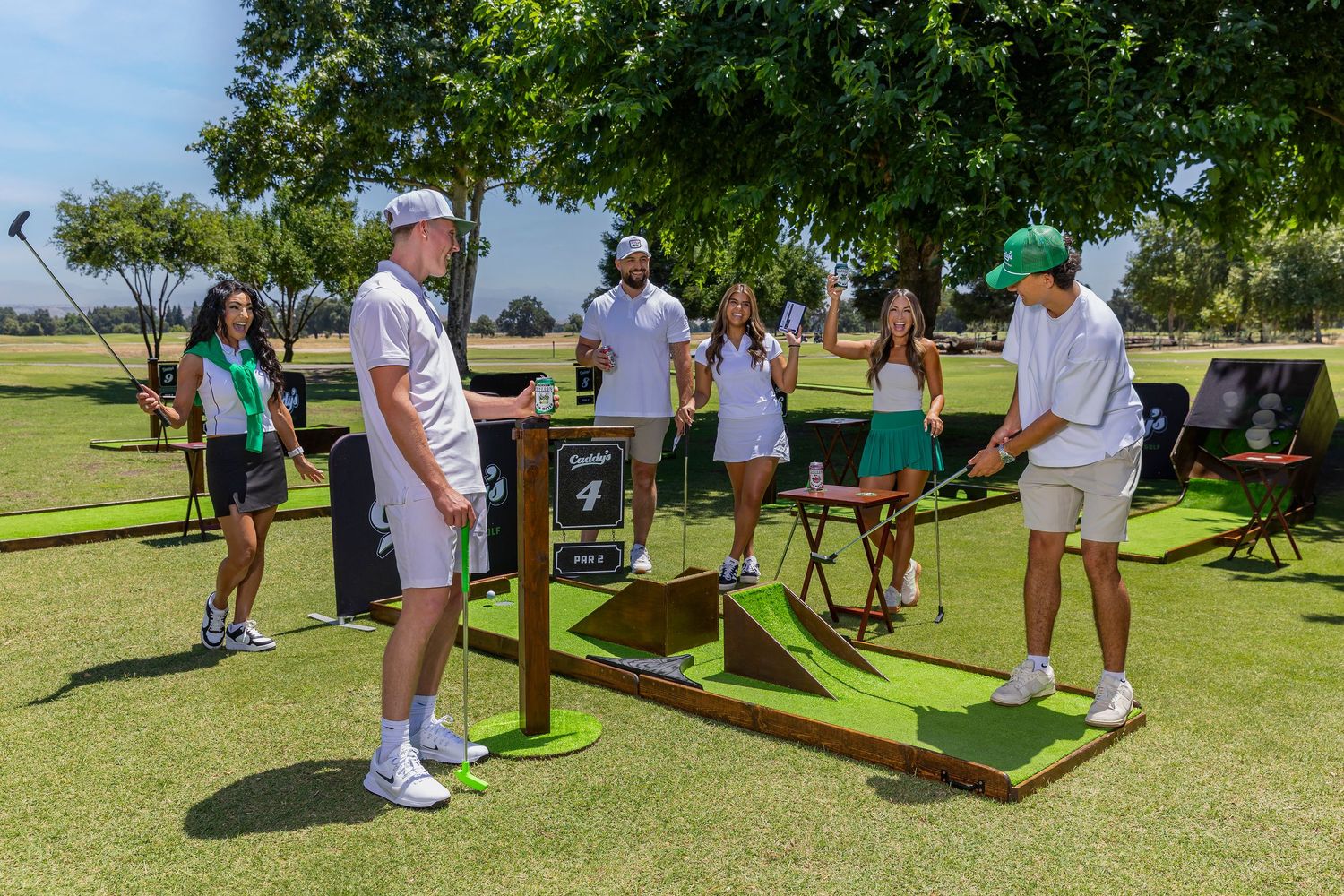 Group of young adults playing mini golf on outdoor course on sunny day at a golf club event.