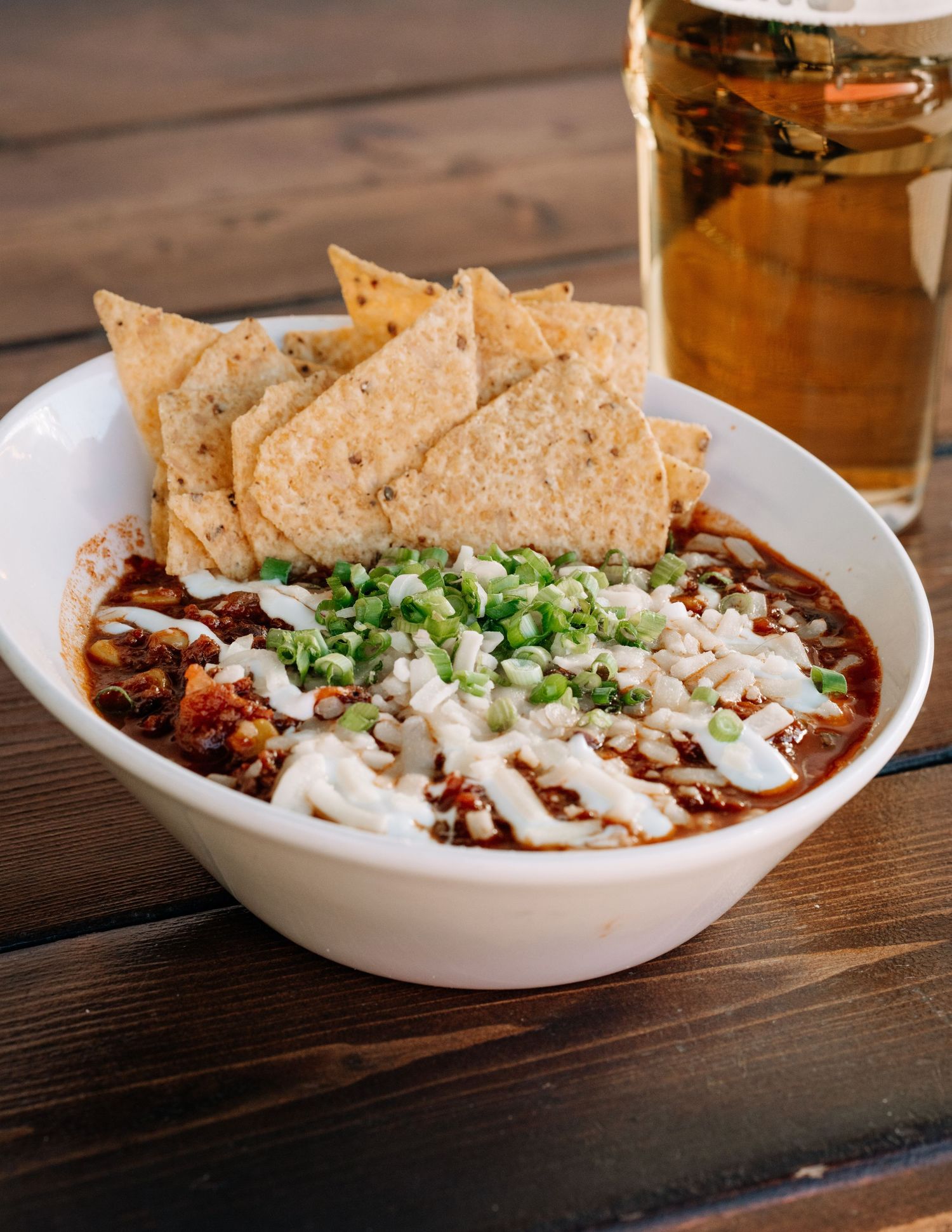 House chili topped with sour cream and tortilla chips beside a pint of beer — photographed for a BC restaurant campaign.