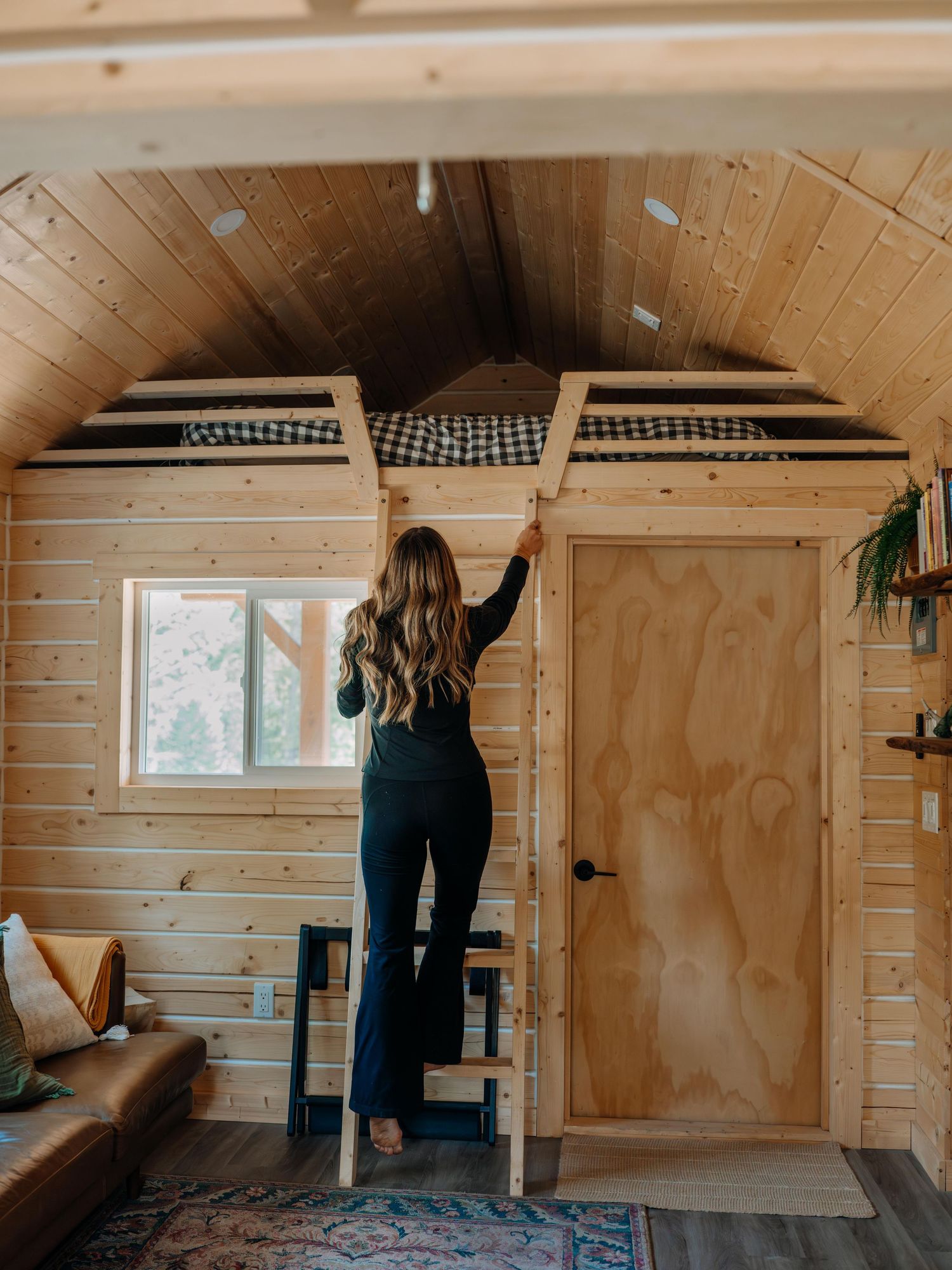 Guest adjusting curtains inside a modern wood cabin — lifestyle and hospitality photography by James Fujita, capturing authentic stays in BC