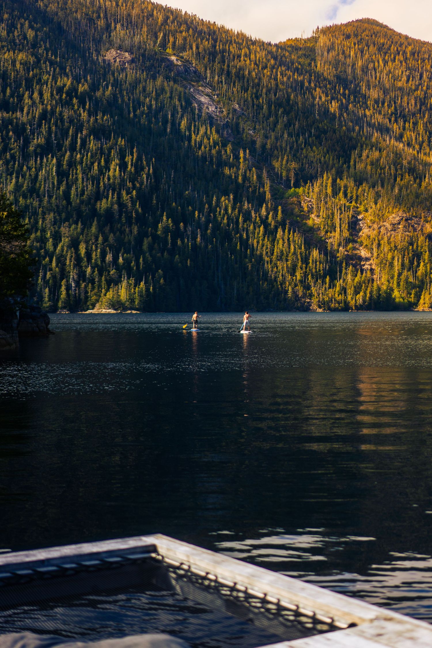 Paddleboarders on a calm mountain lake — resort and lifestyle photography by James Fujita in BC.