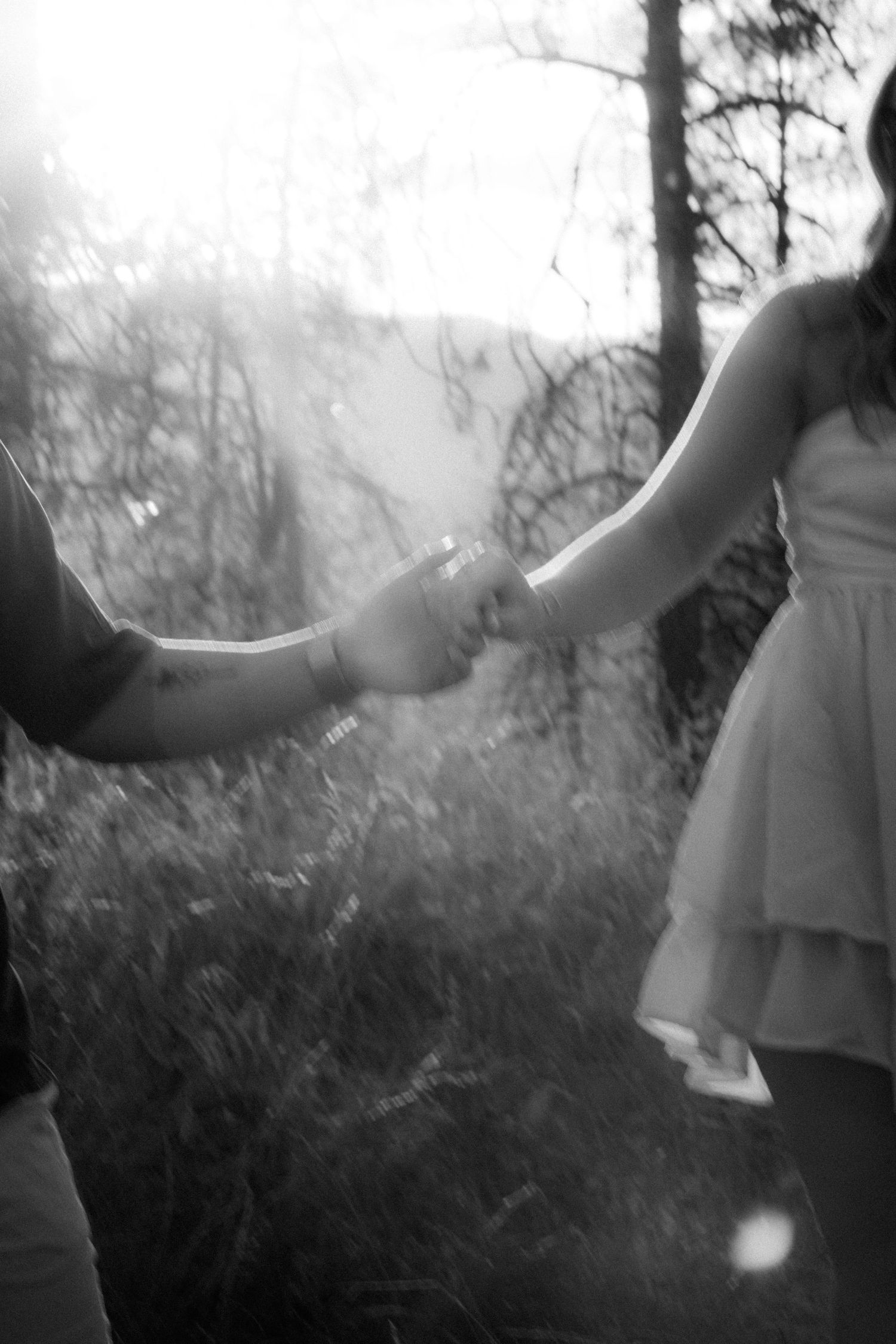 Black-and-white photo of couple holding hands in the forest — artistic lifestyle photography by James Fujita in BC.