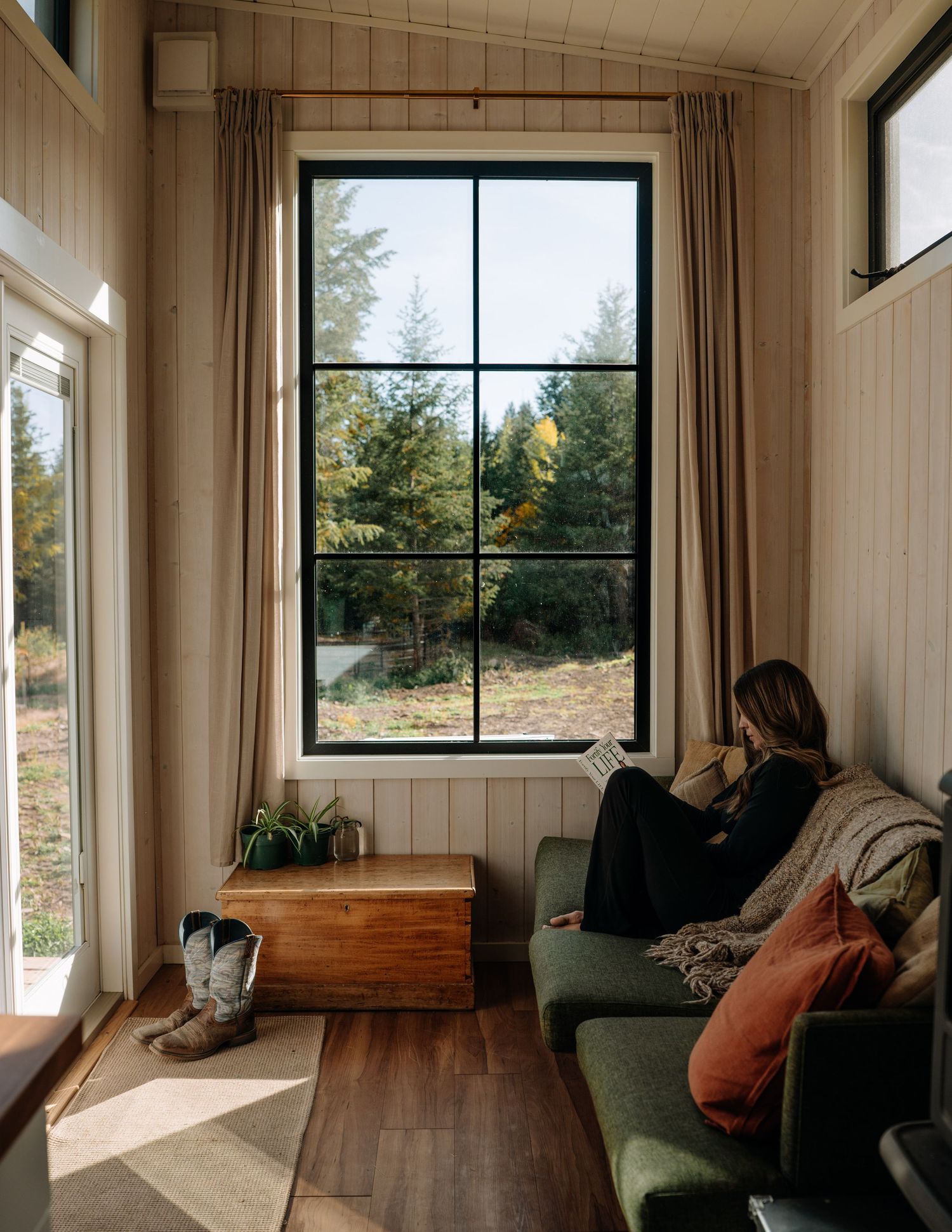 Guest reading beside large window in modern cabin — lifestyle photography in the Okanagan by James Fujita.