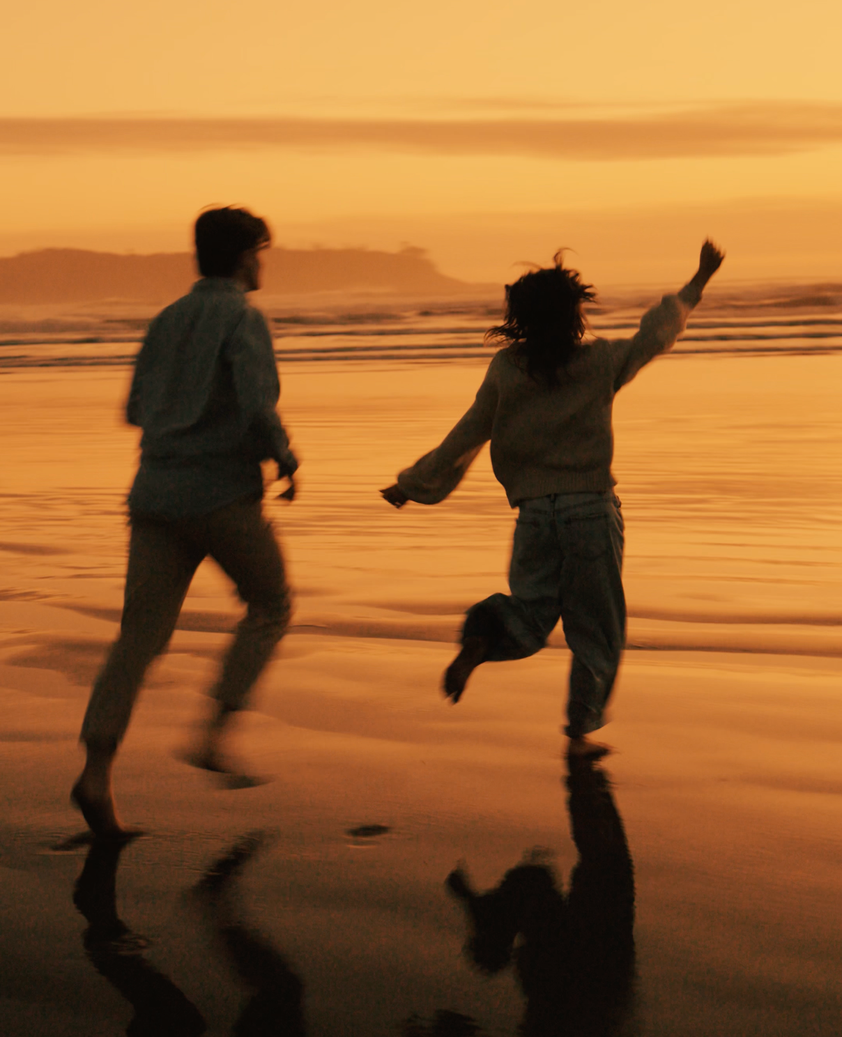 Couple running along Tofino beach at sunset — storytelling travel photography by James Fujita in coastal British Columbia.