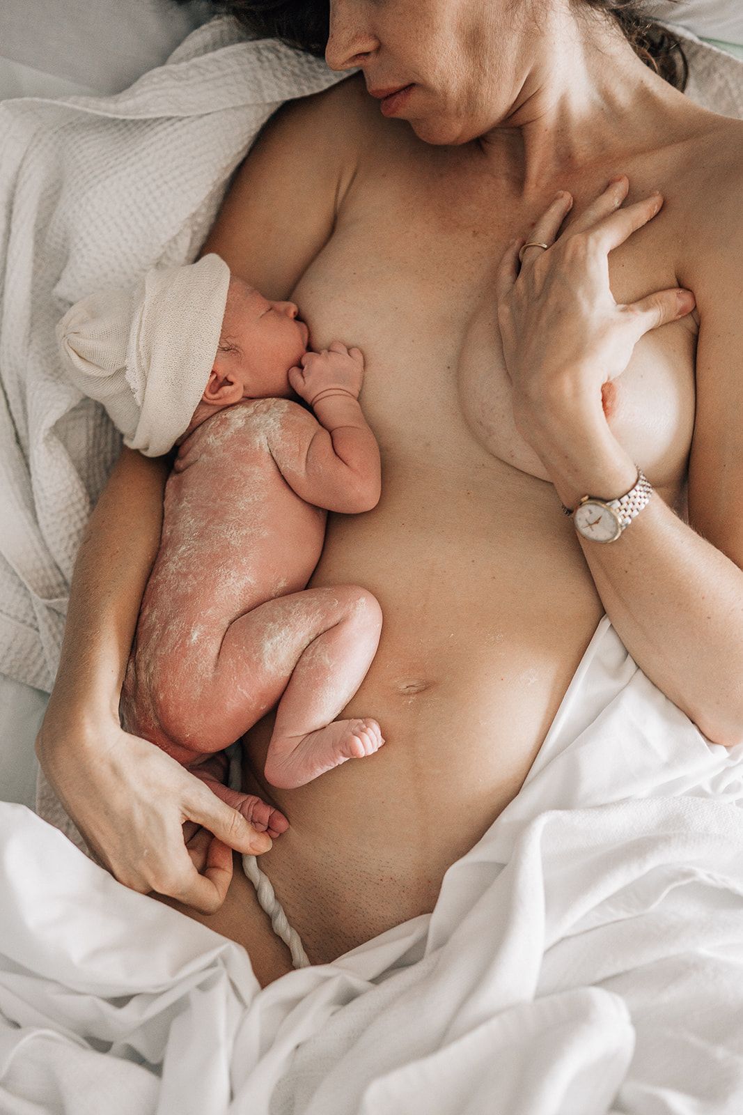 mom nursing her newborn baby still attached with umbilical cord at birth photo shoot in Dubai