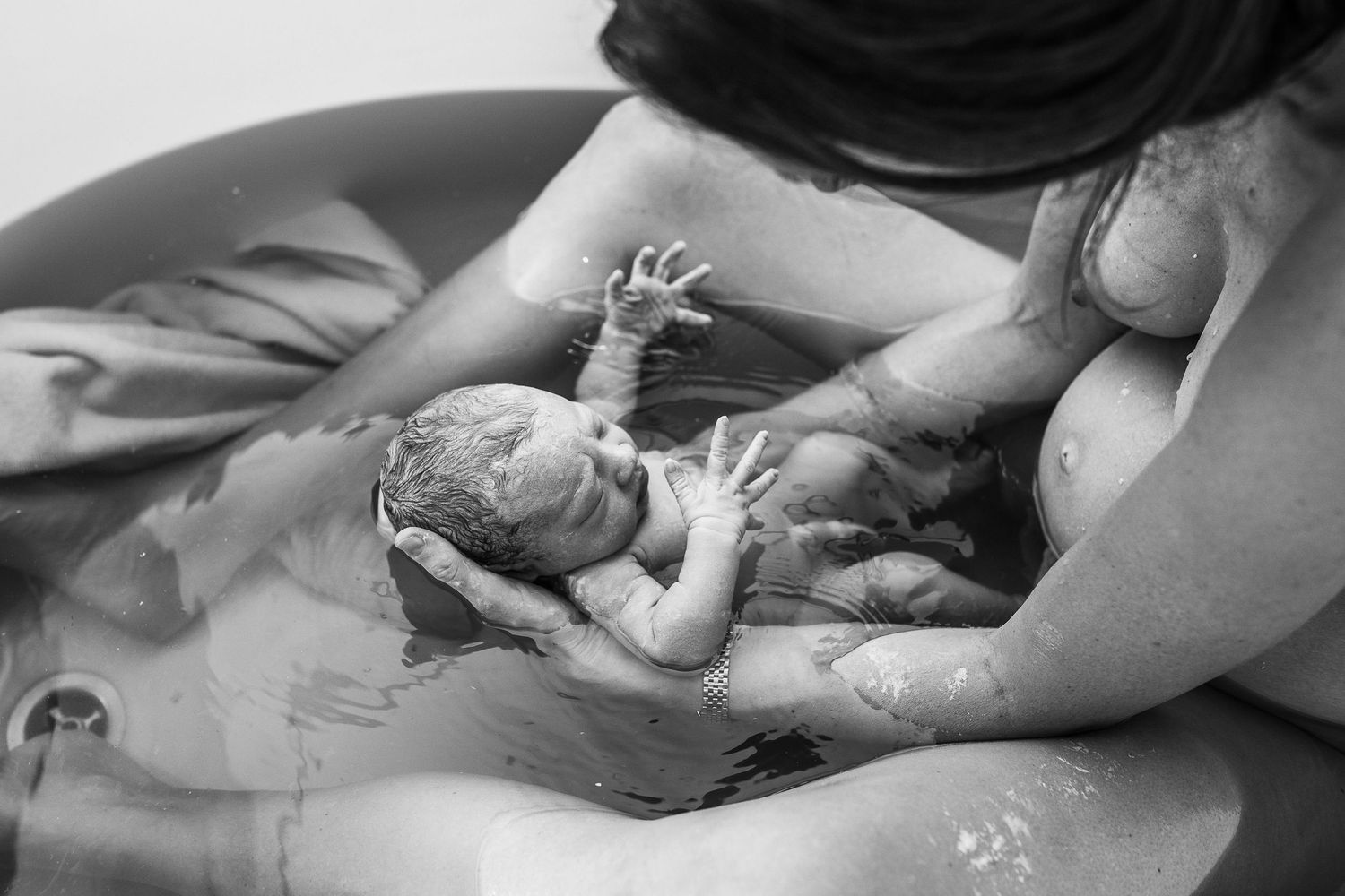 mother pulling her newborn closer to her right after birth in water in dubai hospital