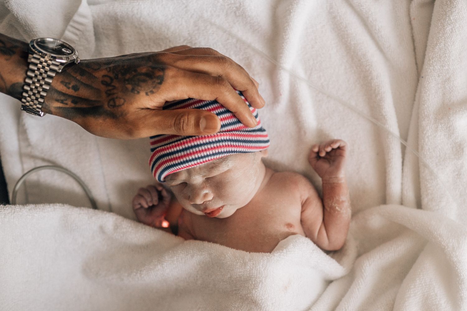 father gently touching his newborn baby by dubai birth photographer