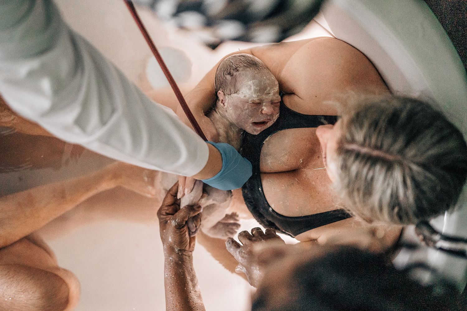 baby being checked while still in a bathtub during water birth captured by dubai birth photographer
