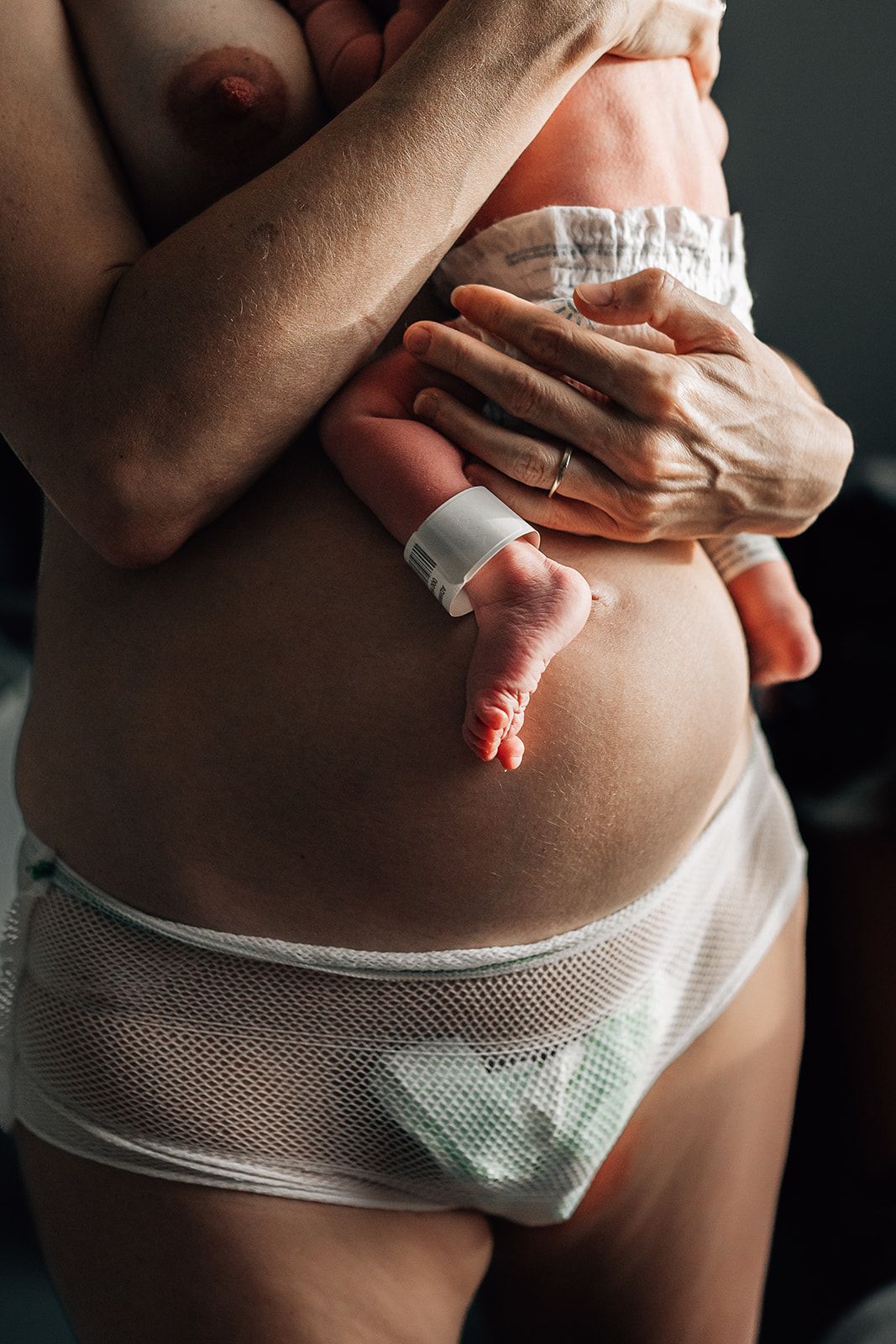 mother wearing hospital mash underwear and holding her baby right after giving birth in dubai