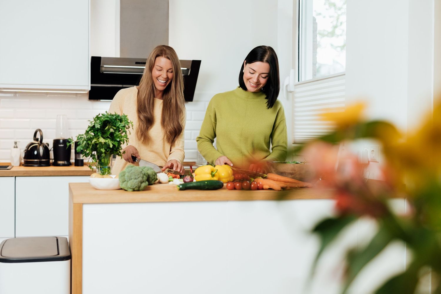 Friends preparing healthy meal together in modern bright kitchen.