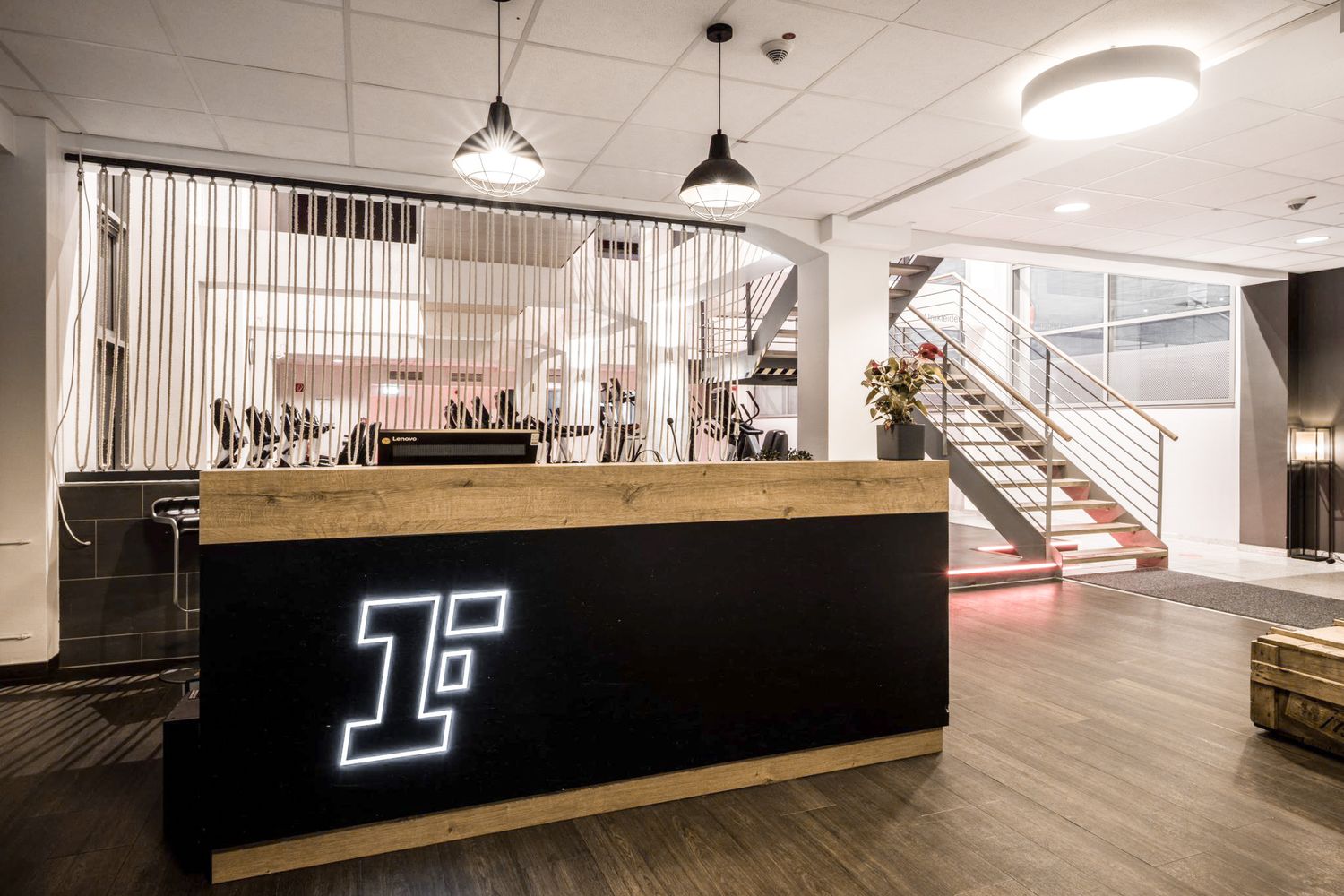 Panoramic view of a sleek modern gym space with dark walls and ambient lighting.