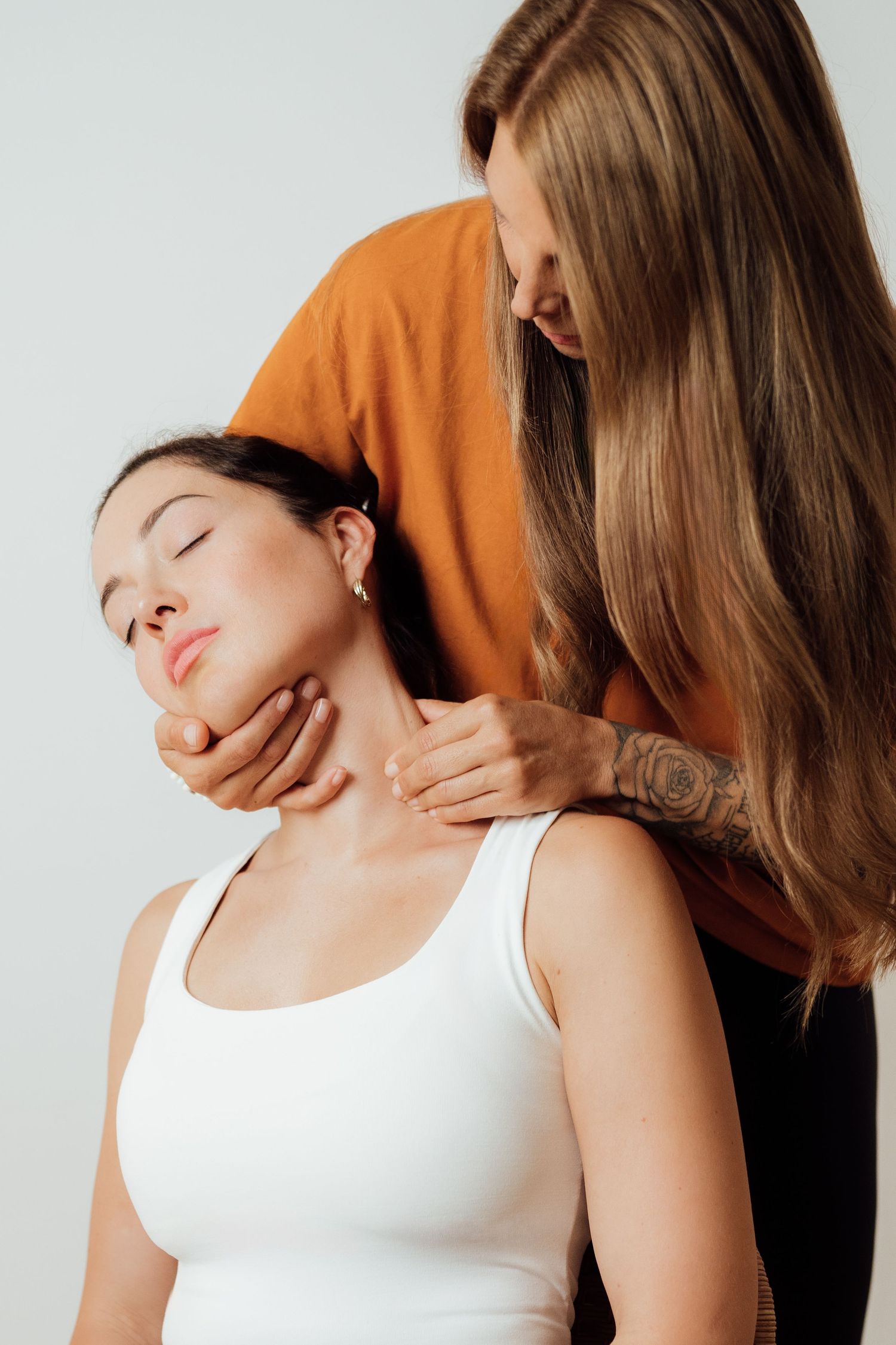 Personal Trainerin Branca unterstützt Klientin durch Schmerztherapie bei einer sanften Übung gegen Nackenverspannungen & Kopfschmerzen.
