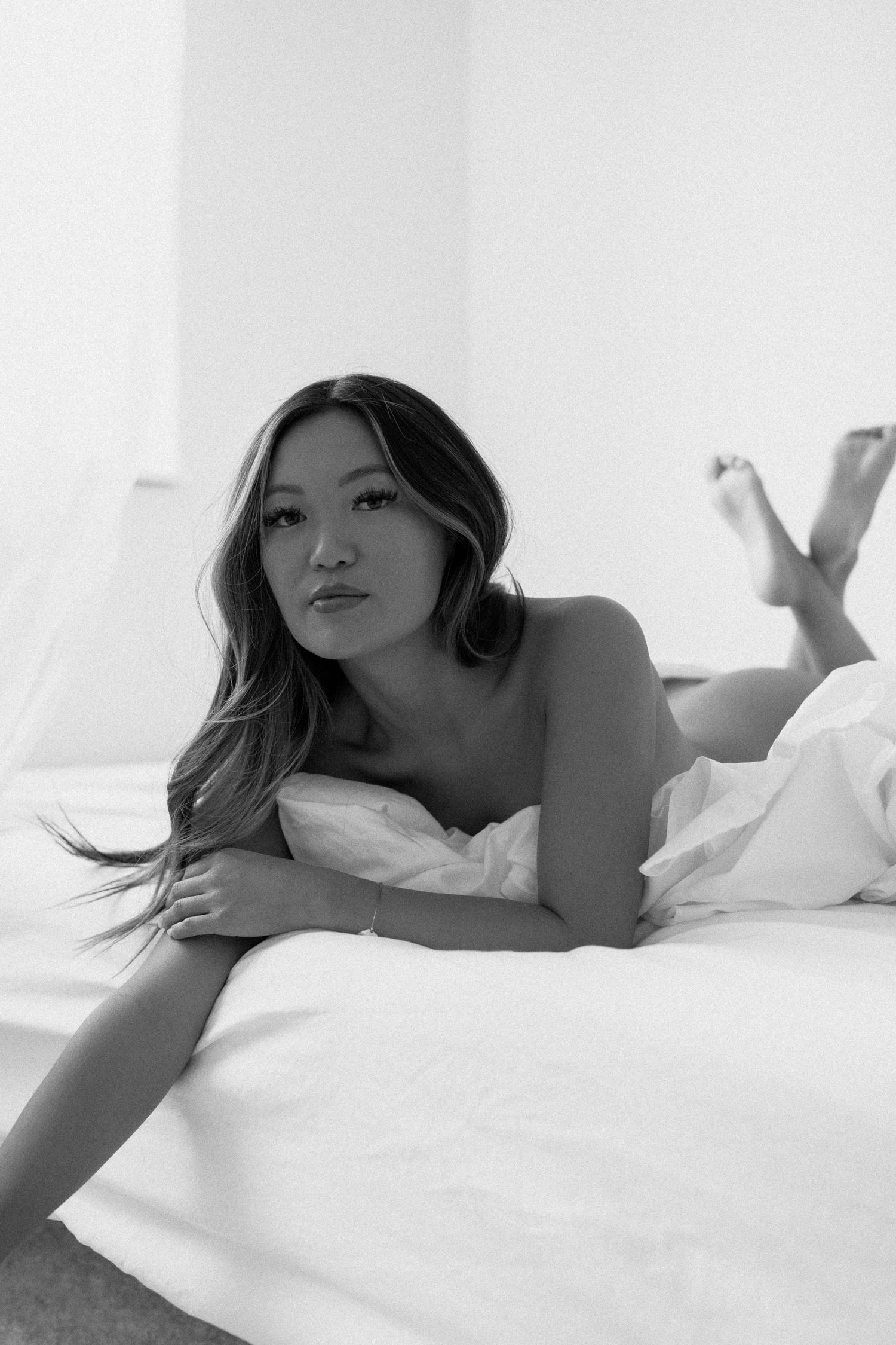 Artistic boudoir image captured on bed with minimal styling