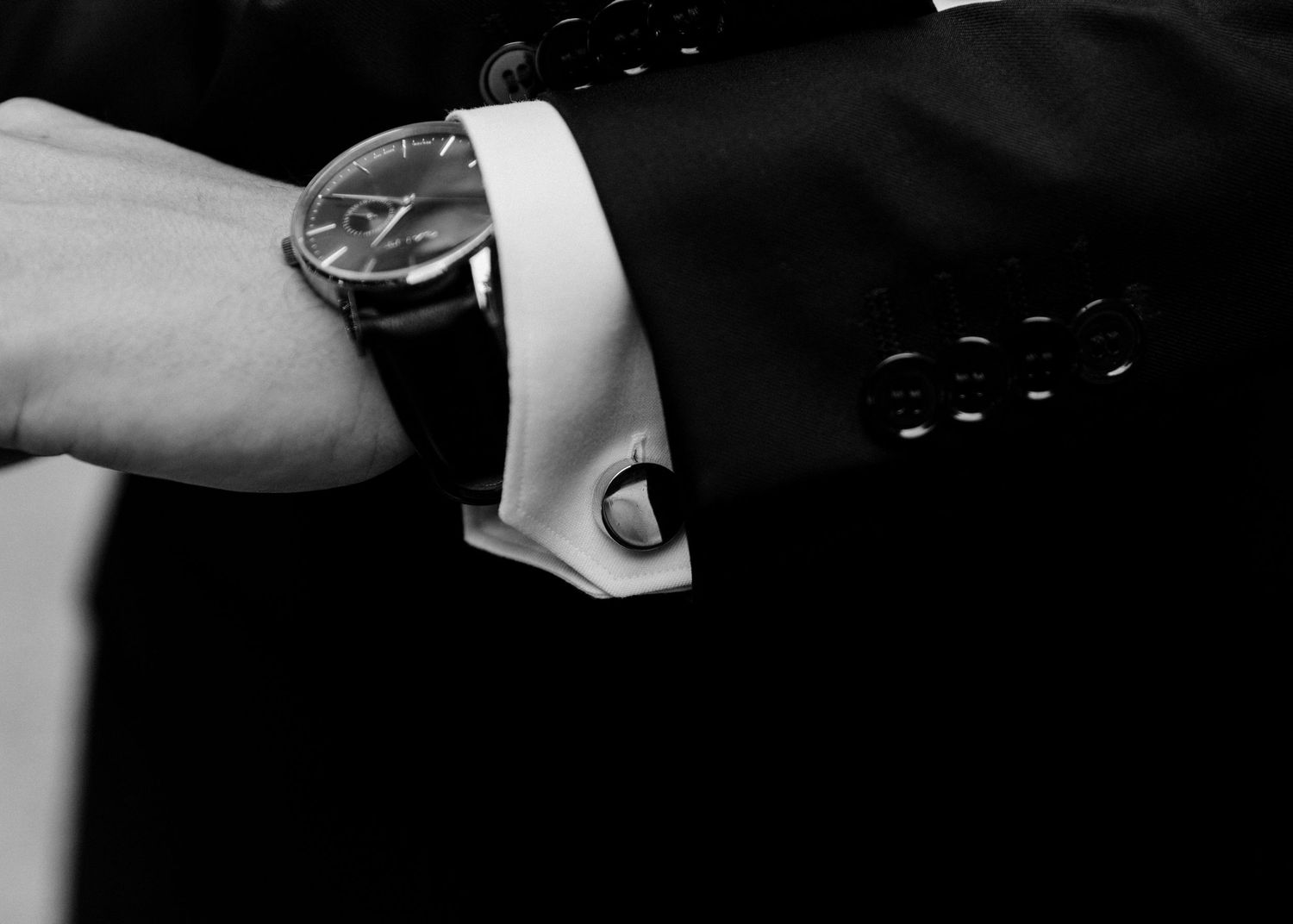Black and white detail shot of a formal watch and white cuff.