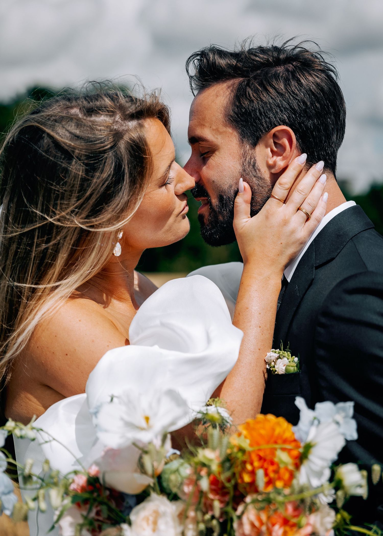 Intimate wedding moment captured in wheat field with bright summer flowers.