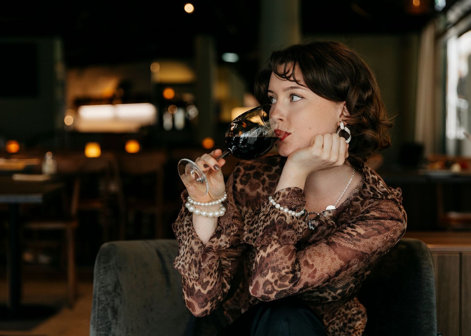 Person enjoying a drink in a dimly lit venue with warm ambient lighting.