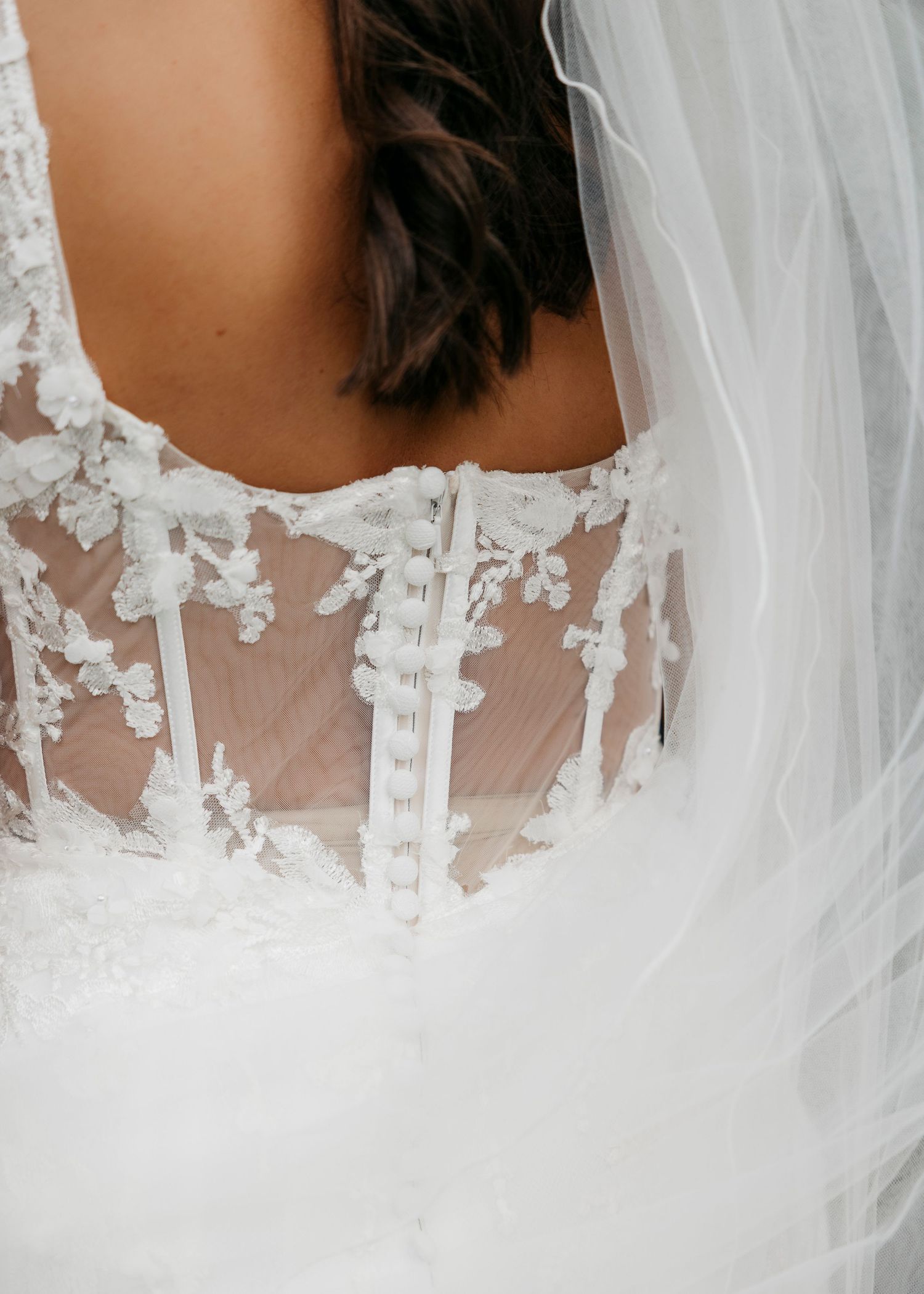 Intricate lace detail on back of wedding dress with sheer fabric and floral appliques.