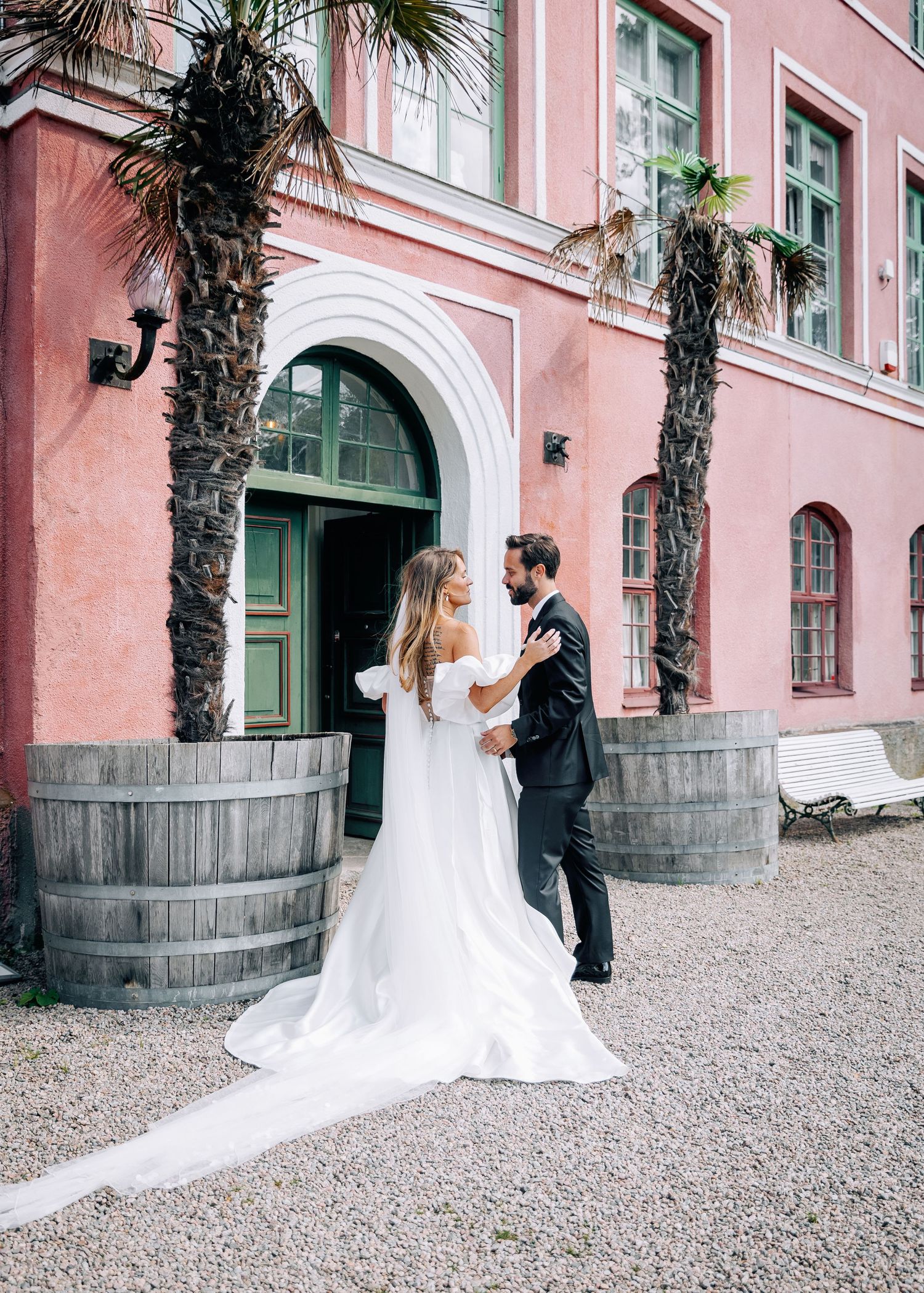 Series of romantic wedding photos against a pink building with palm trees and gravel path.