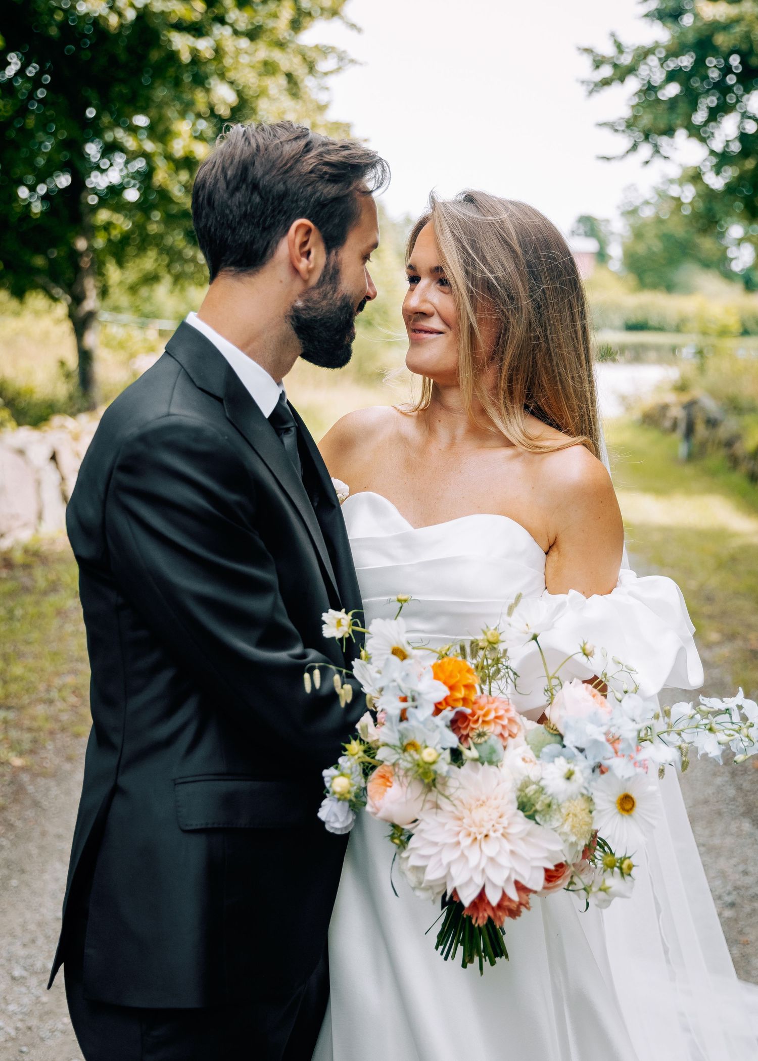 Romantic wedding couple embracing outdoors with colorful bouquet.