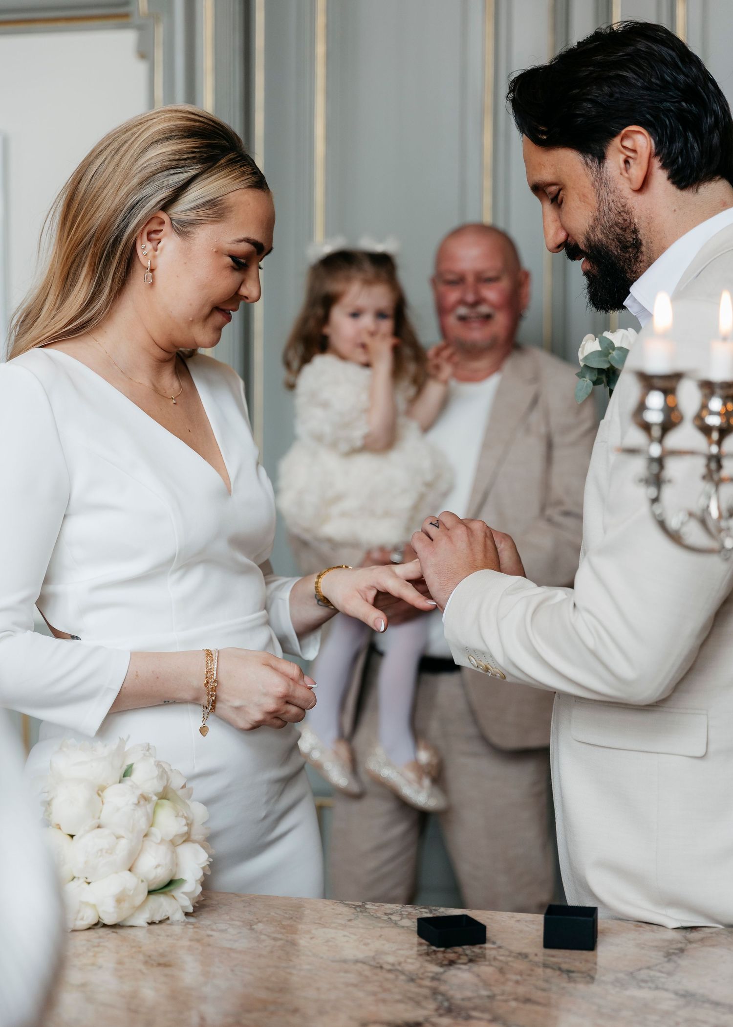 Ring exchange ceremony during an intimate wedding with guests watching.