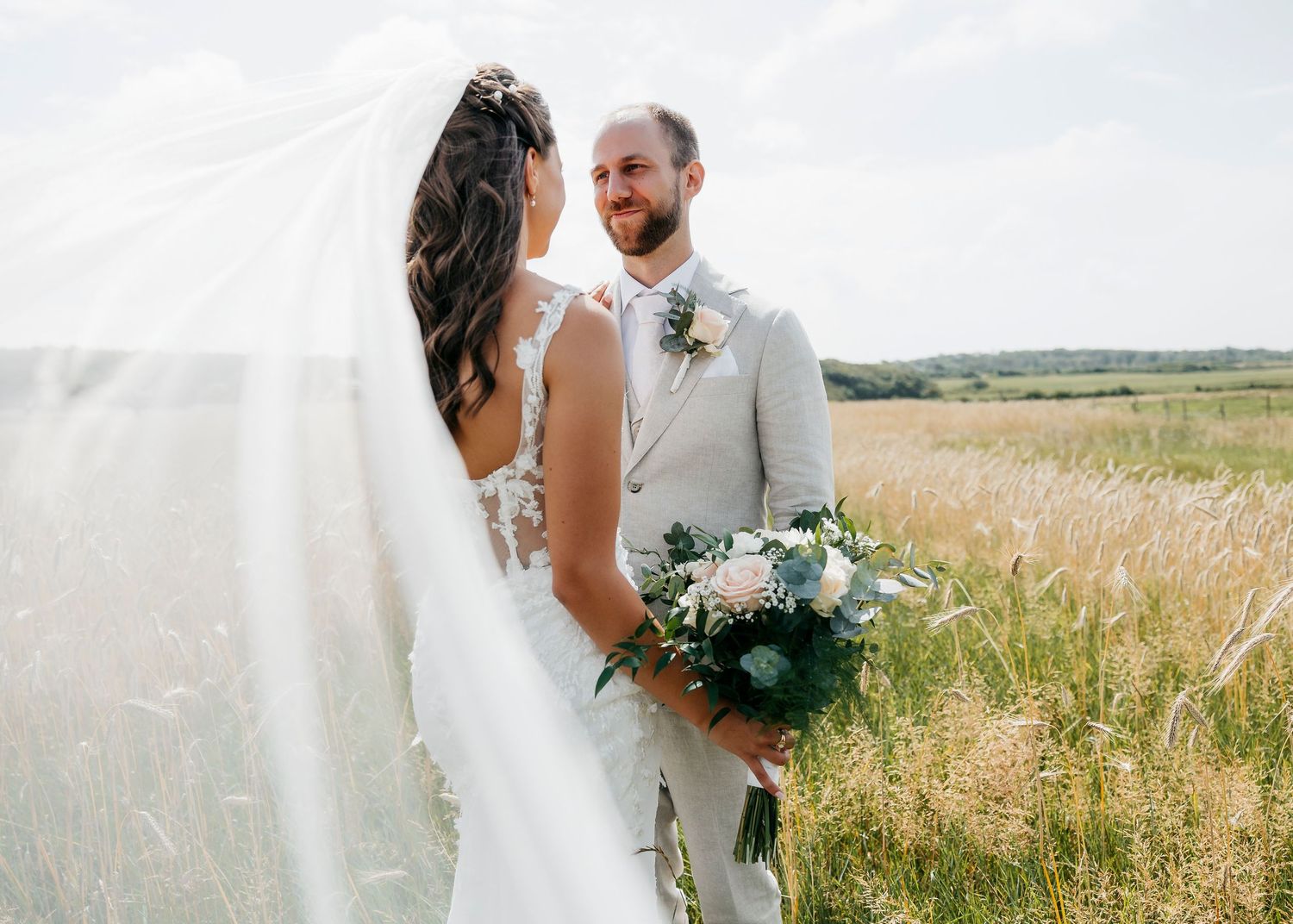 Wedding couple sharing intimate moments in a rustic wheat field setting.