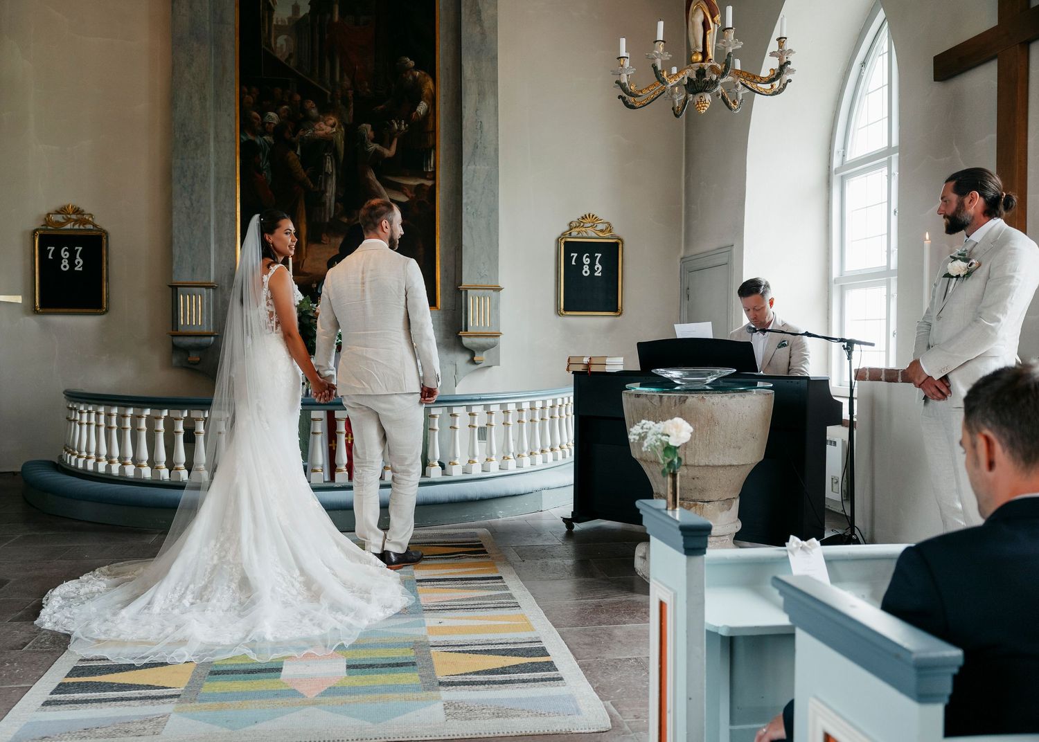 Interior shots of church wedding ceremony with classic architectural details and chandeliers.