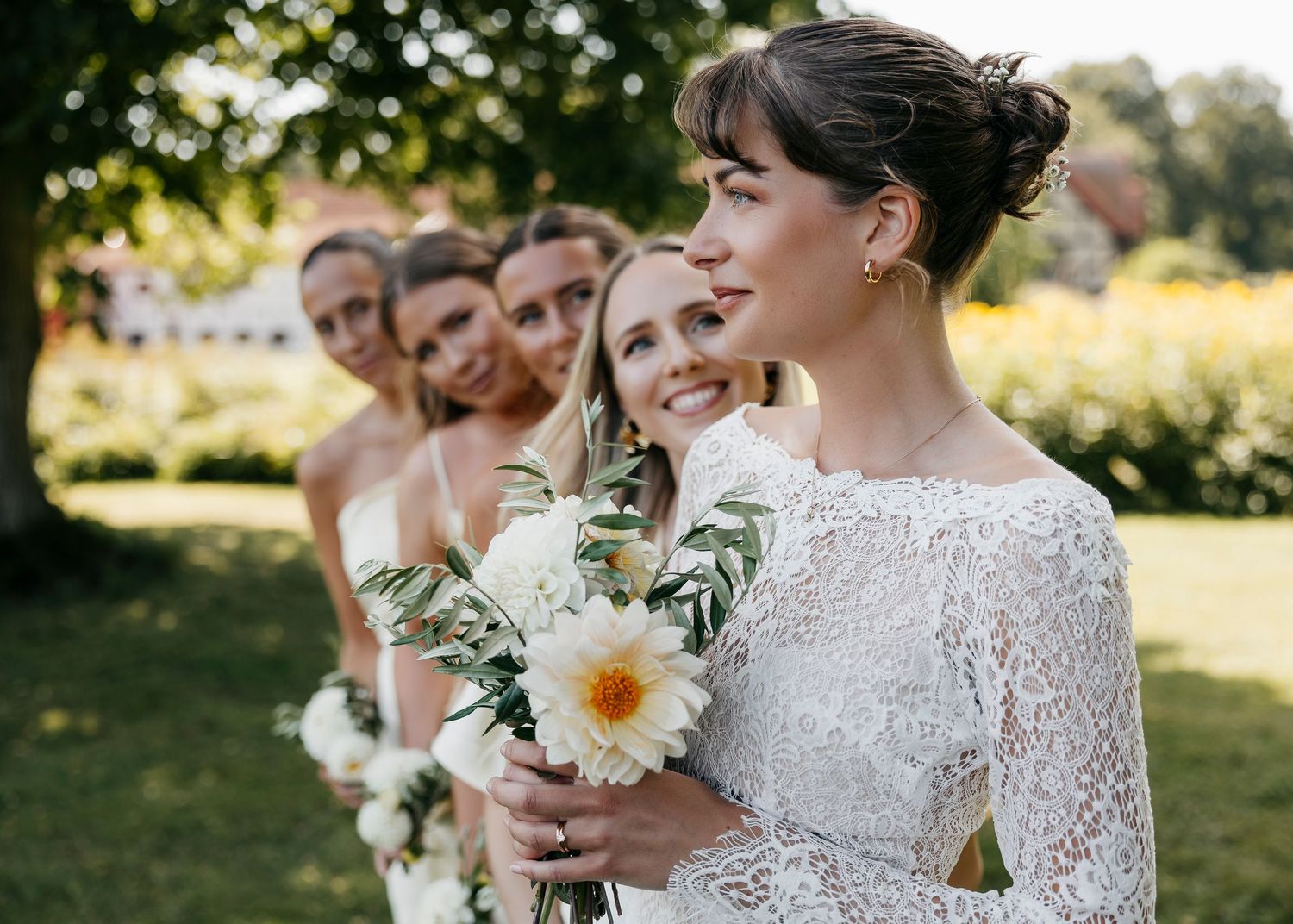 Wedding couple and party members share candid moments in outdoor garden setting.
