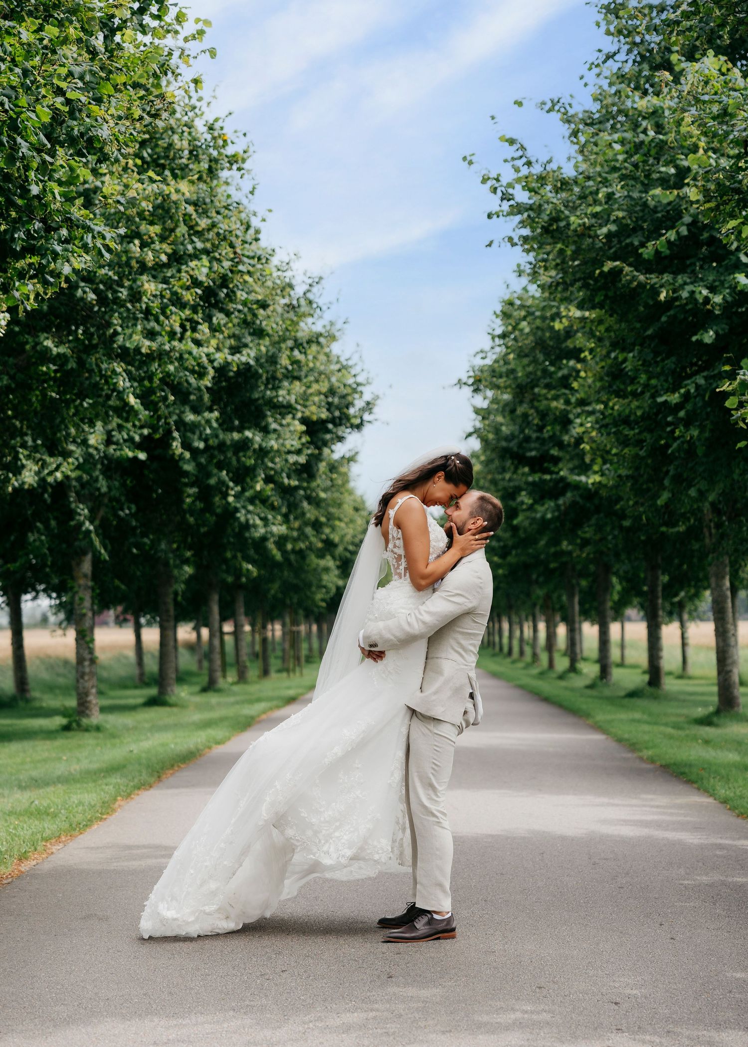 Tree-lined path serves as backdrop for romantic wedding poses.