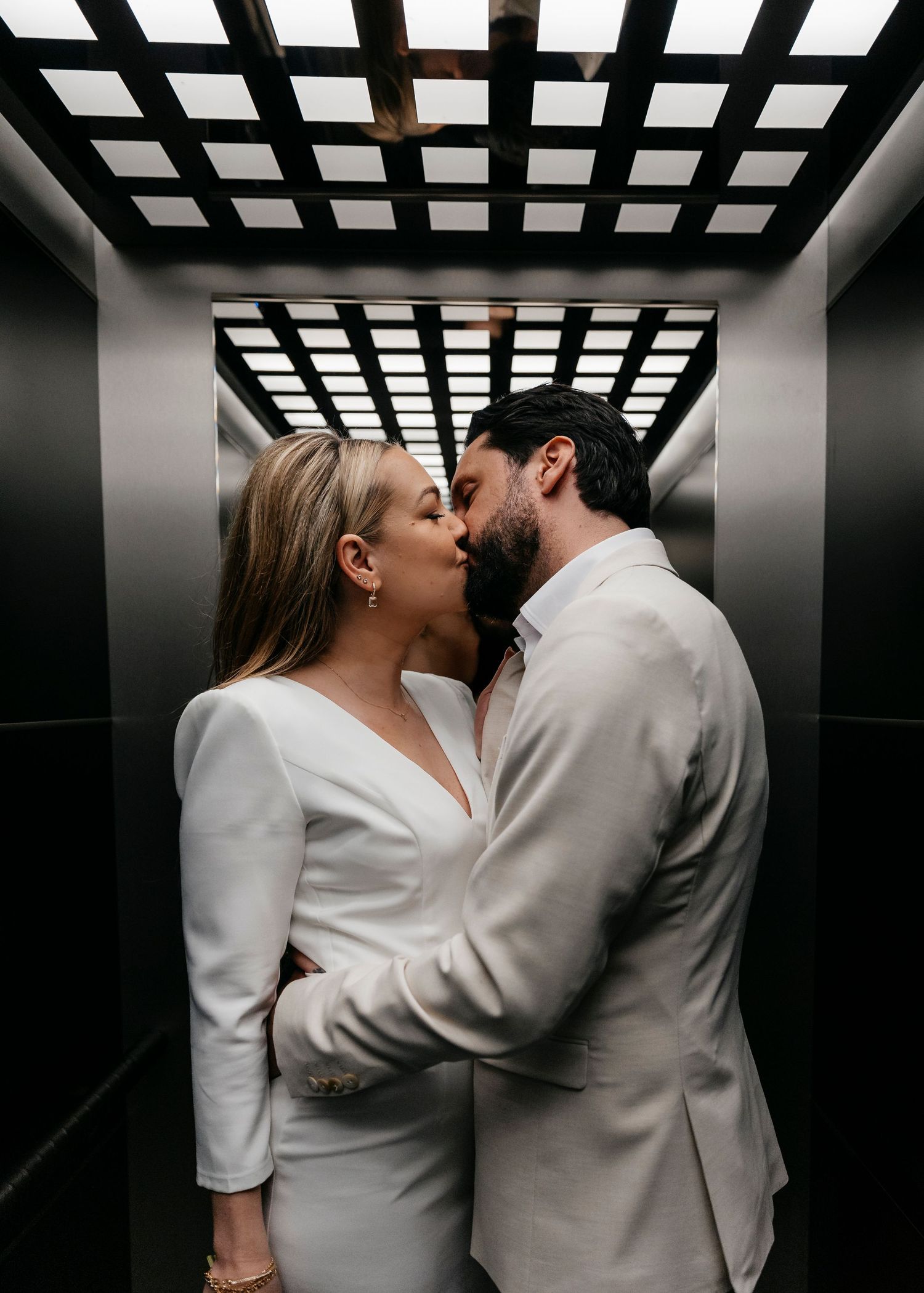 Intimate wedding couple moment captured in modern elevator with geometric lighting.