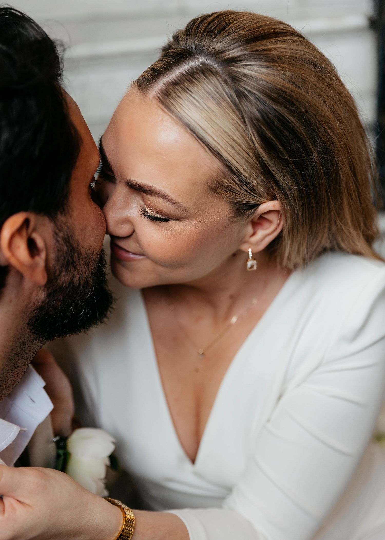 Close-up shots capture intimate moments between a couple in white formal wear.