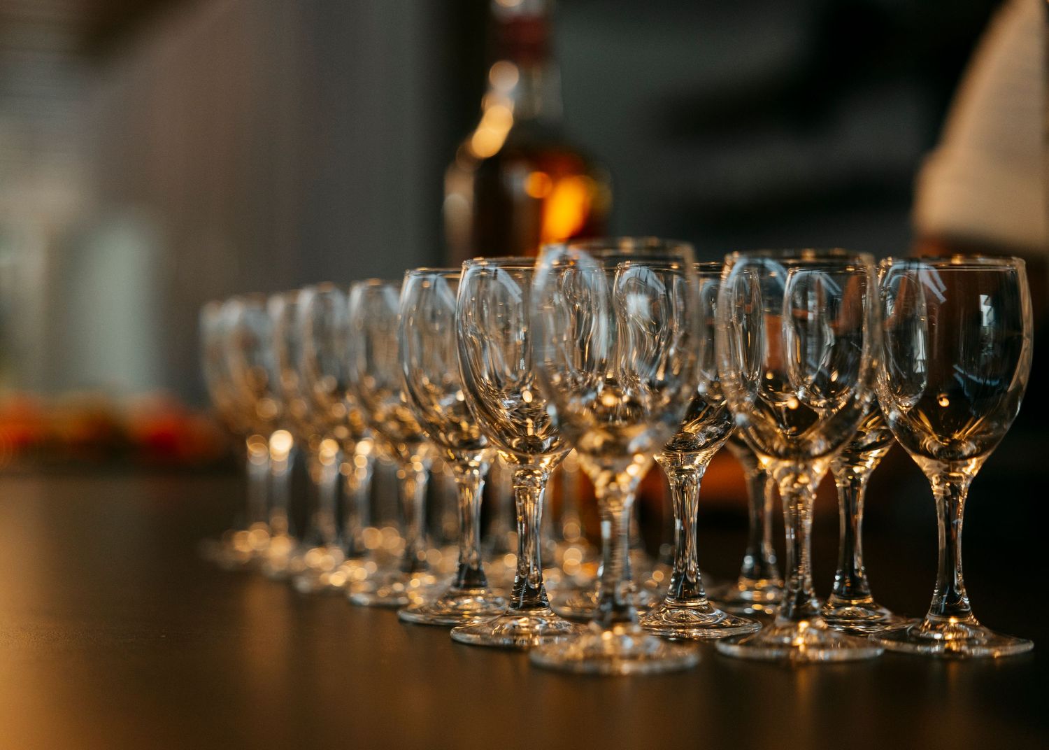 Long row of empty champagne glasses lined up on dark surface.