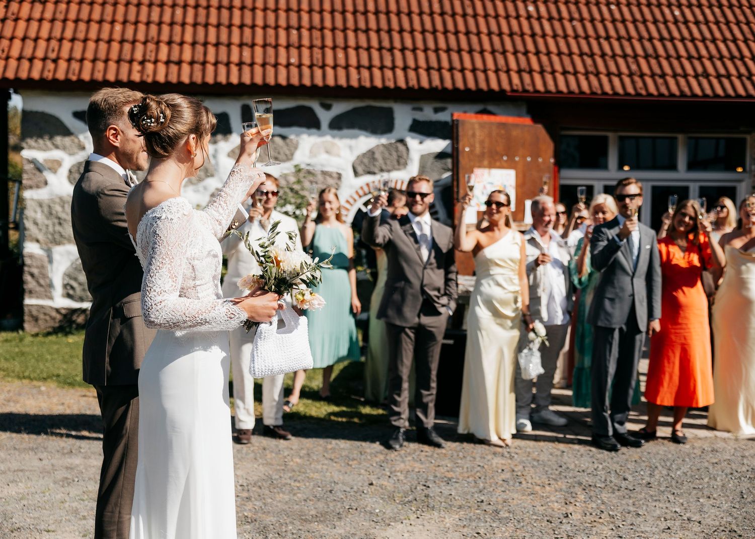 Wedding guests gather outside venue under terra cotta roof tiles.