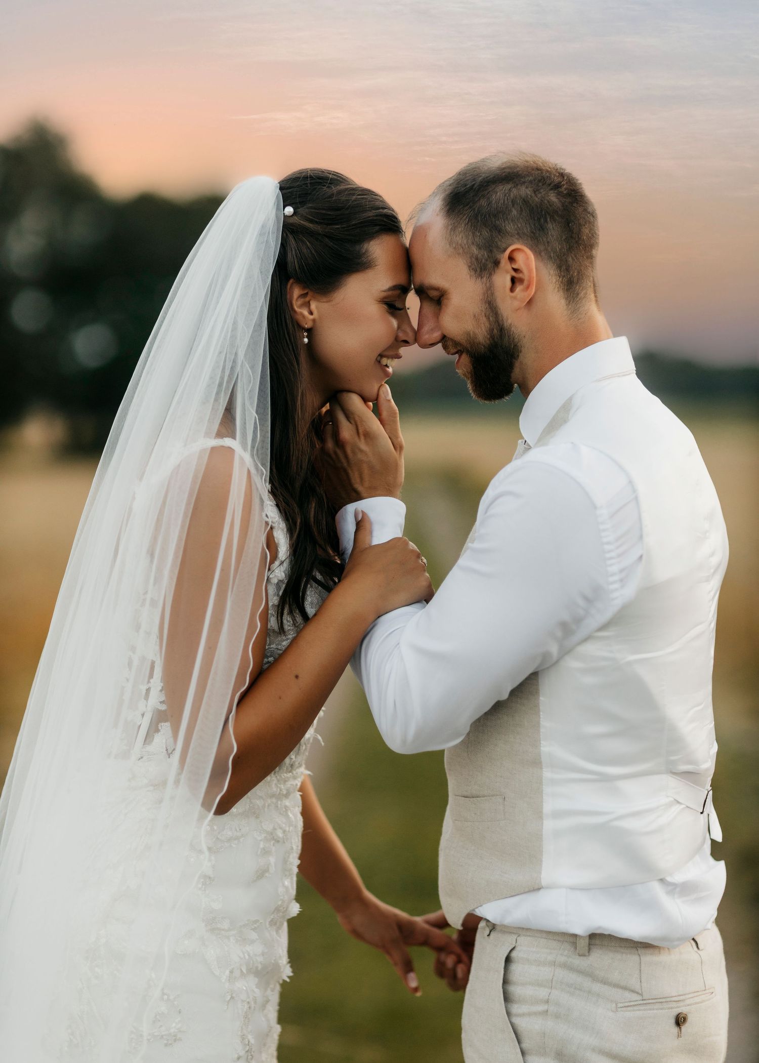 Romantic wedding portraits in a field during sunset.