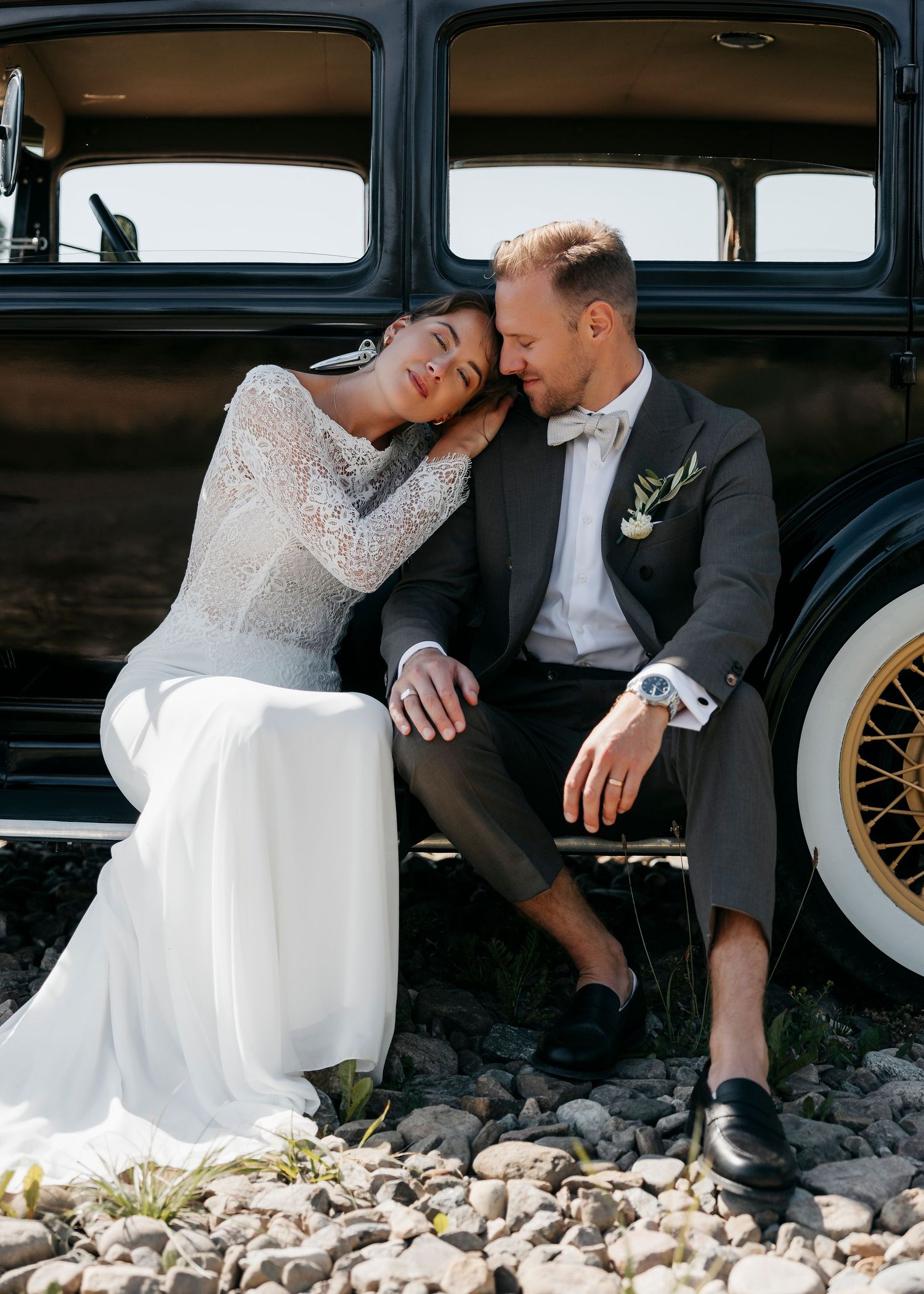 Couple shares intimate moment while sitting on vintage car running board.