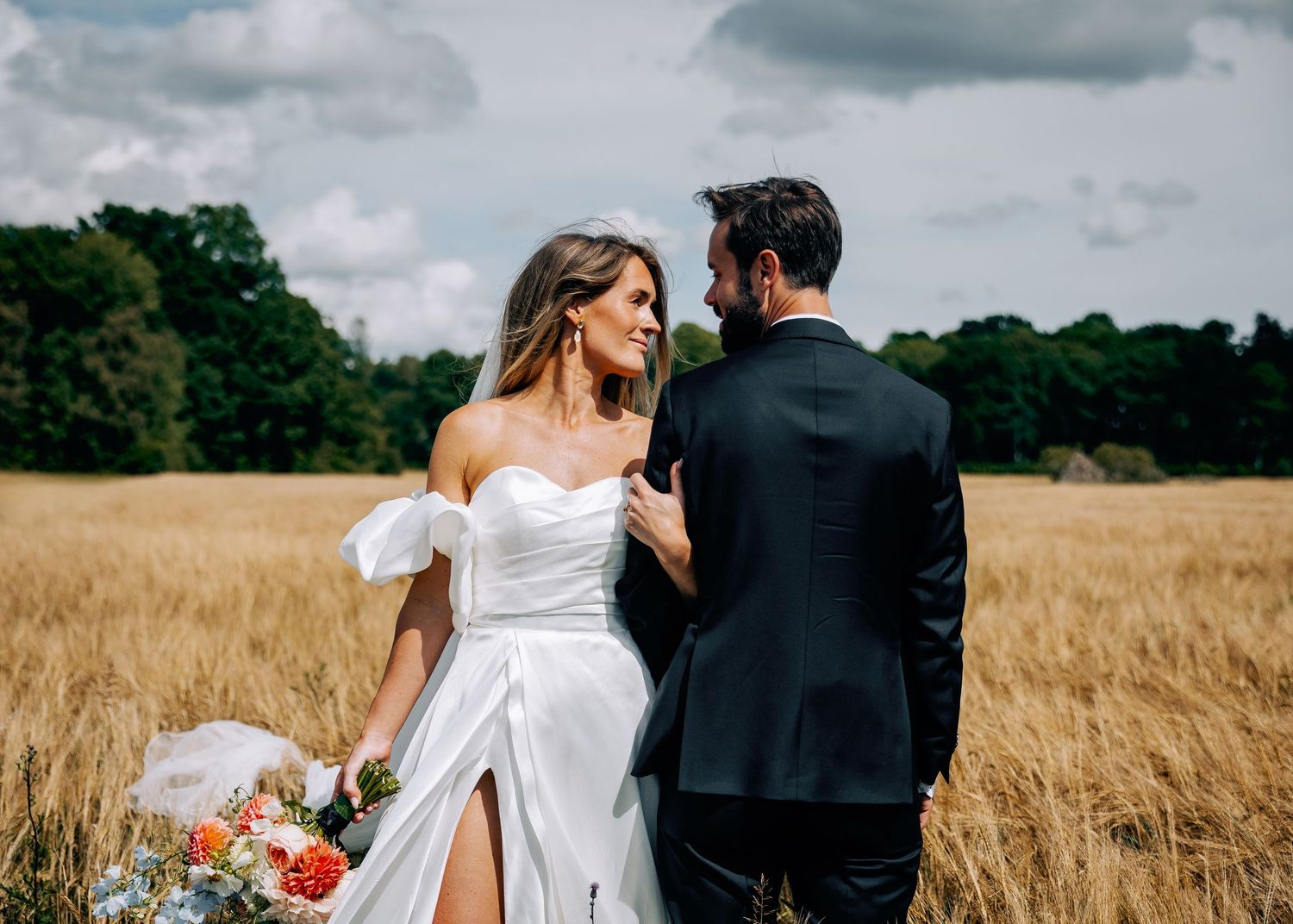 Newlyweds share an intimate moment together in a rustic wheat field on their wedding day.