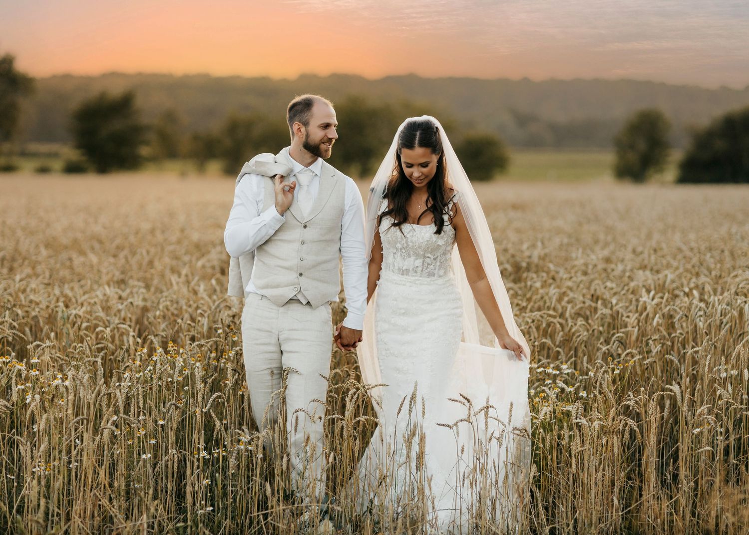 Wedding couple embracing in a wheat field during golden hour.