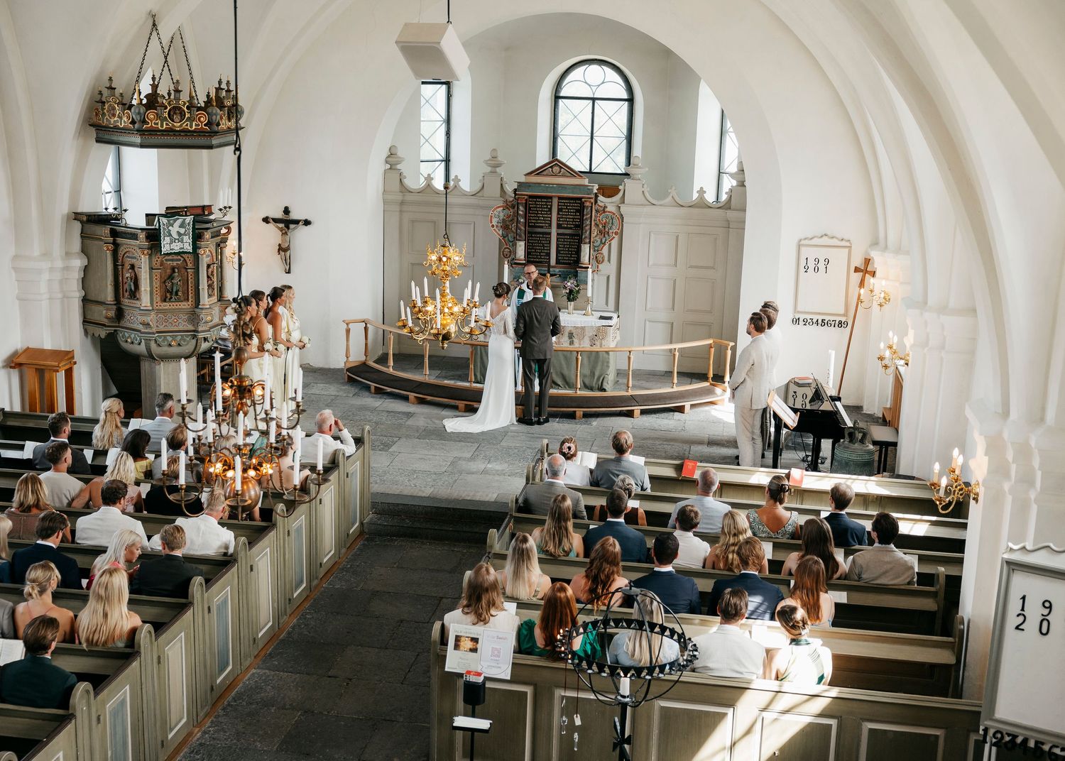 Wide angle view of church wedding ceremony showing full interior architecture and guests.