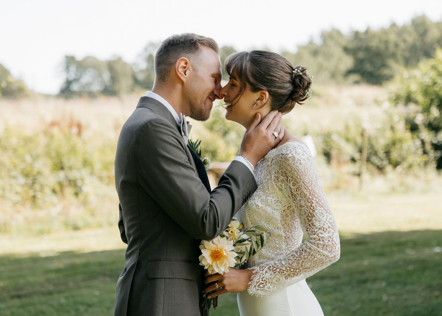 An intimate wedding moment captured in a sun-drenched field with yellow flowers.
