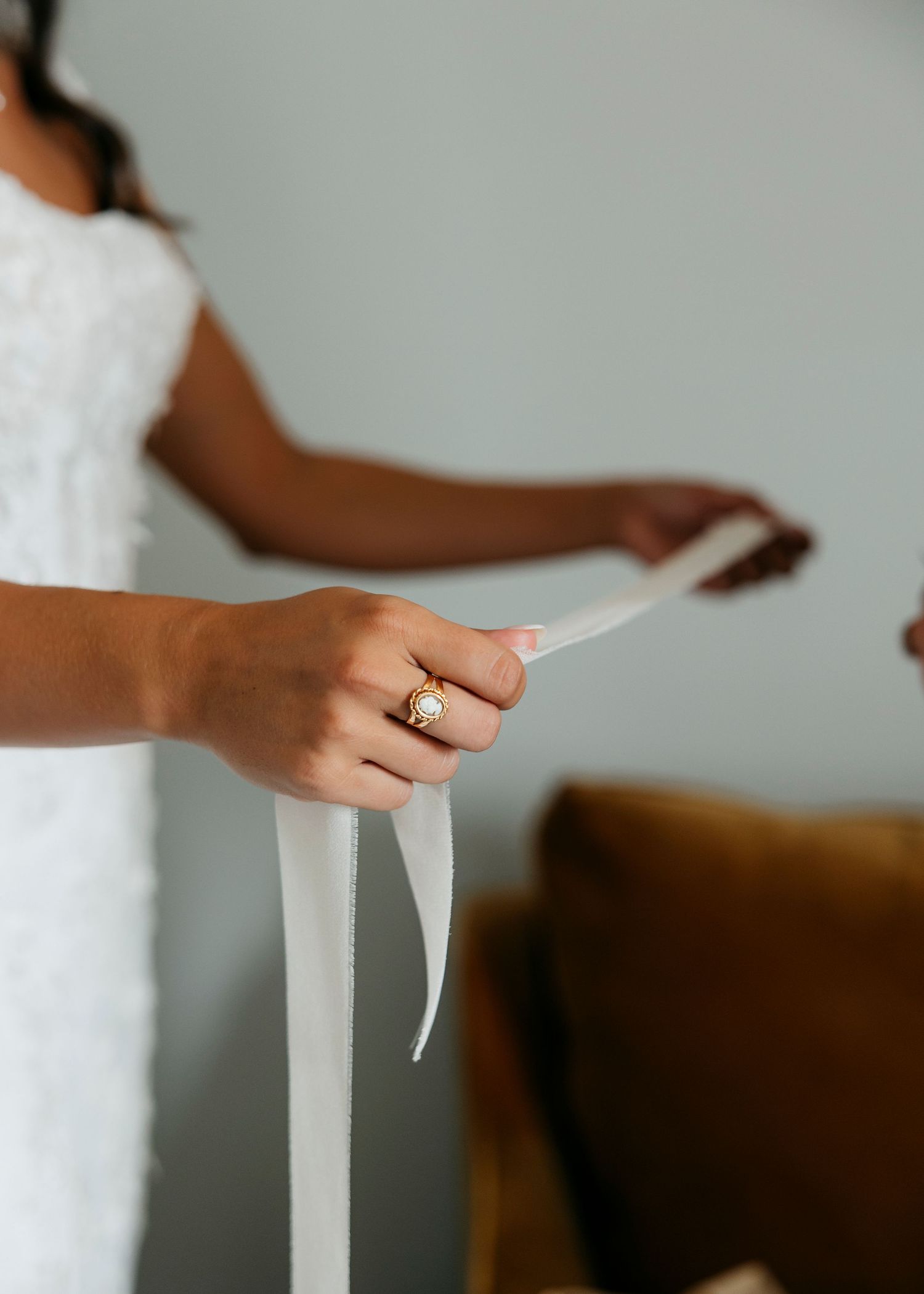 Hands delicately adjusting a flowing white wedding veil against a light background.