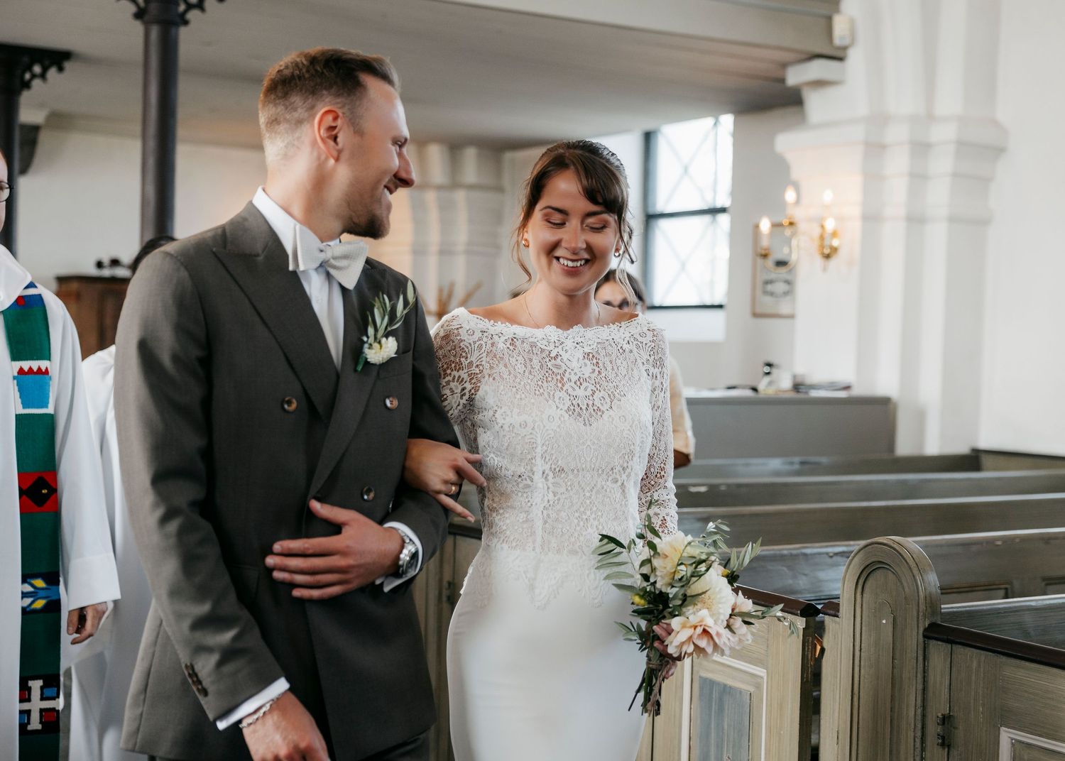 Wedding ceremony taking place inside historic white church with traditional decor.