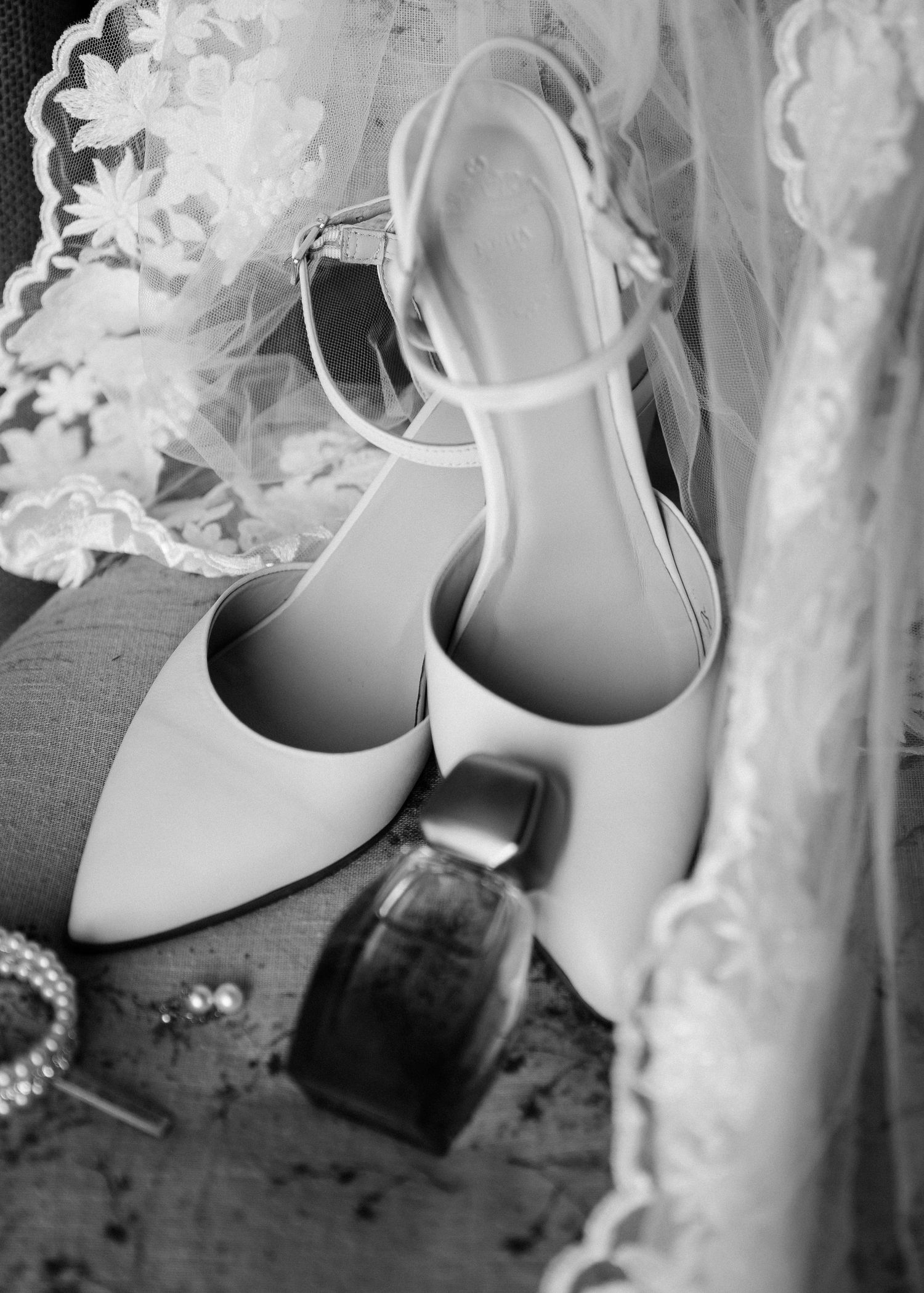 Elegant white bridal shoes with pearl details displayed against lace fabric.