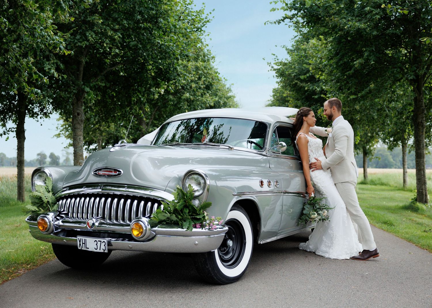 Vintage silver Buick car displayed at an outdoor wedding with trees in the background.